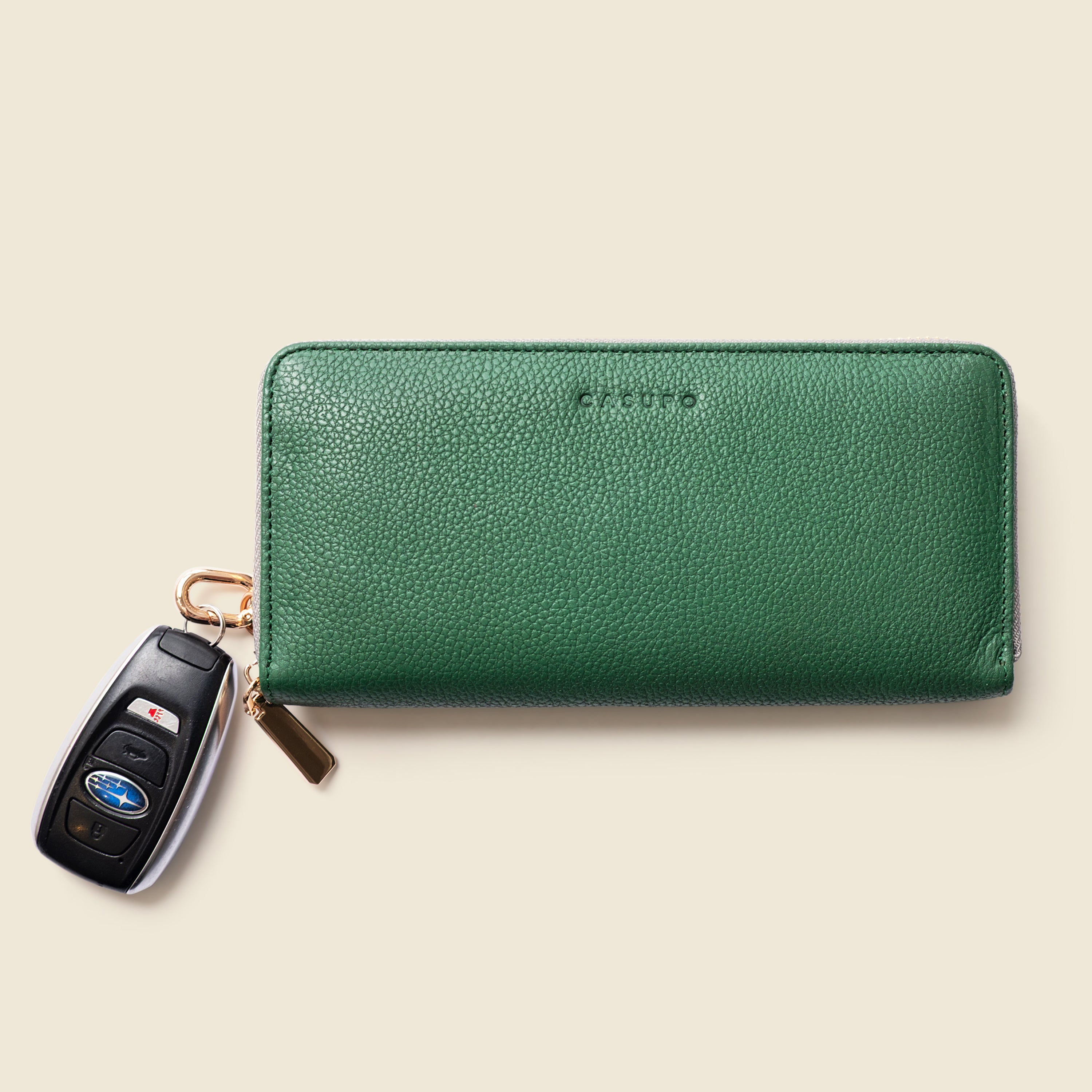 Green wallet with a keychain on a beige background