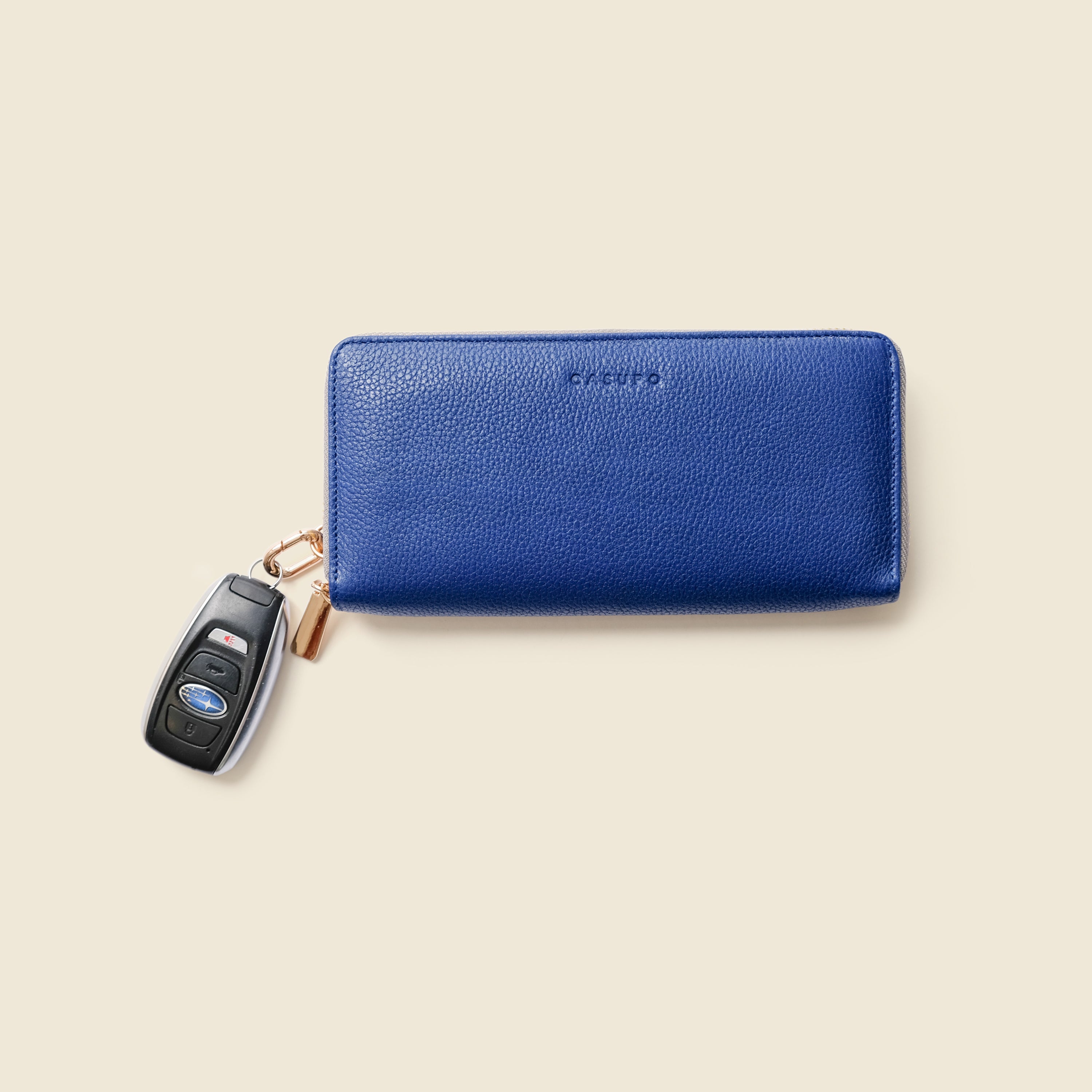 Blue wallet with a keychain on a beige background