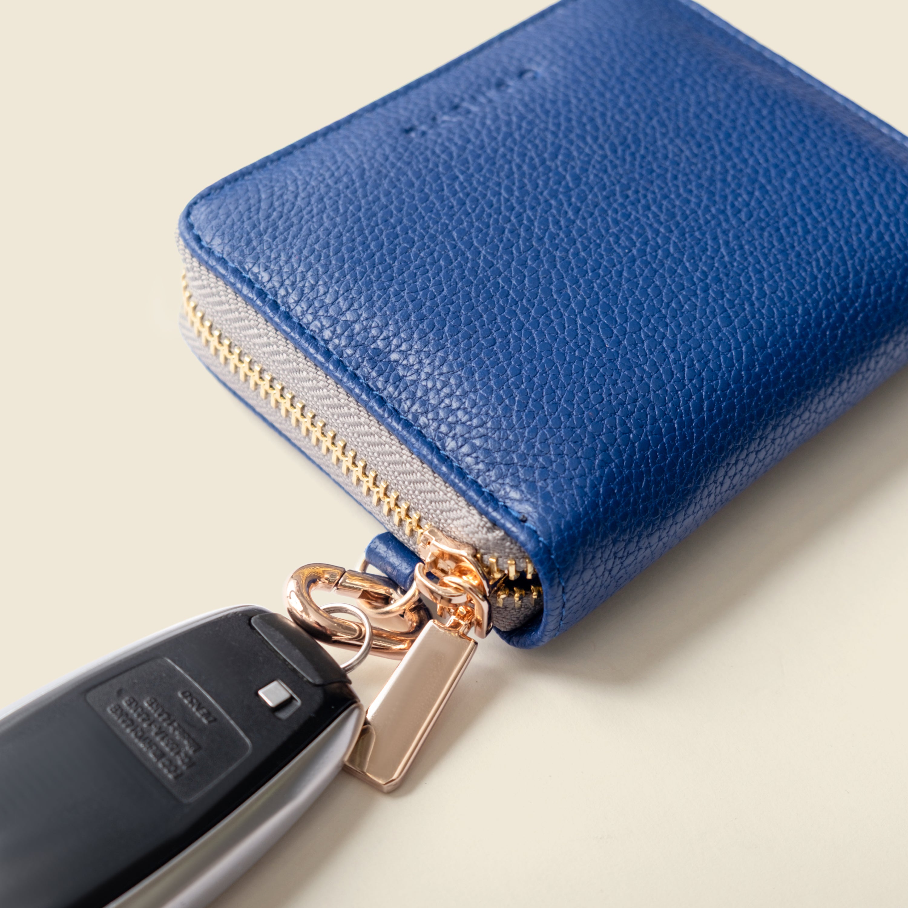 Blue leather wallet with a keychain attached on a light beige background