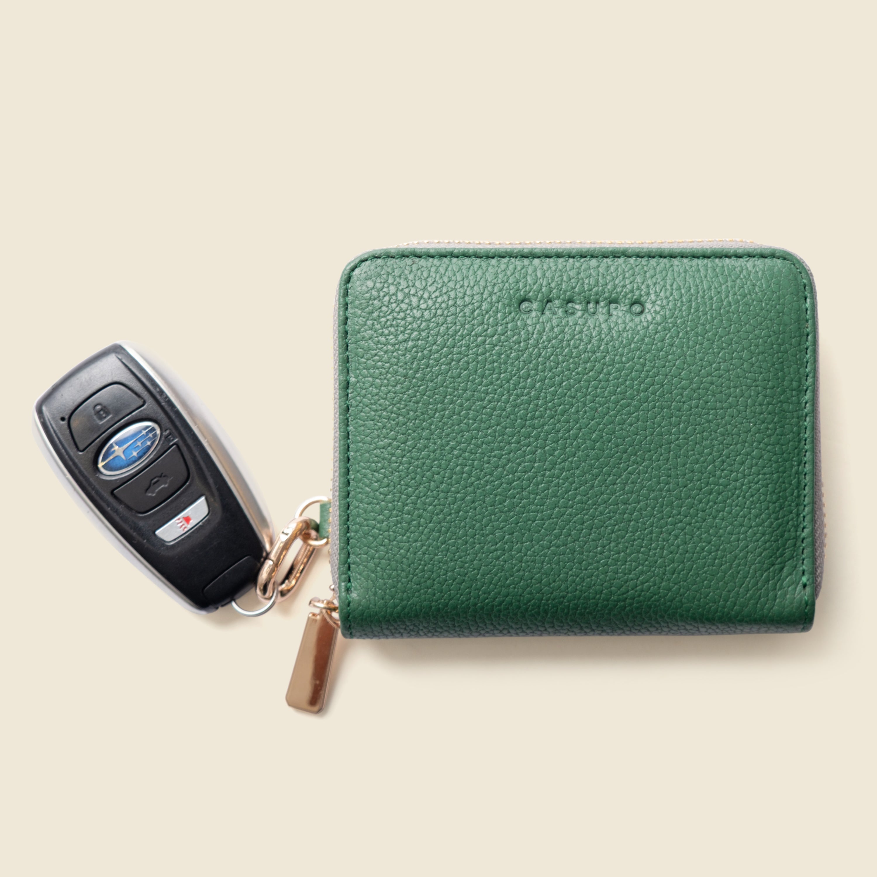Green wallet with a key fob on a beige background