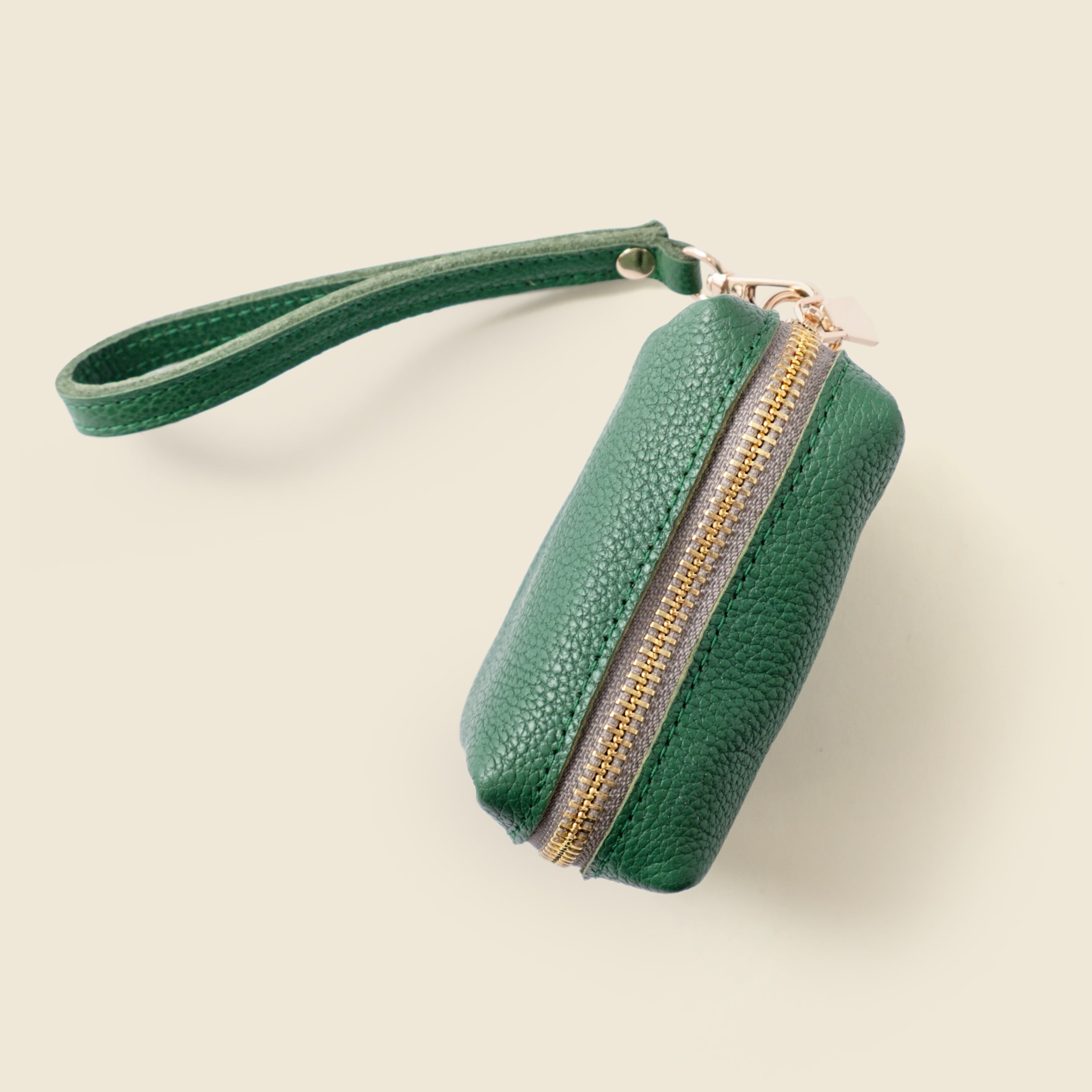 Green leather clutch with gold zipper on a beige background
