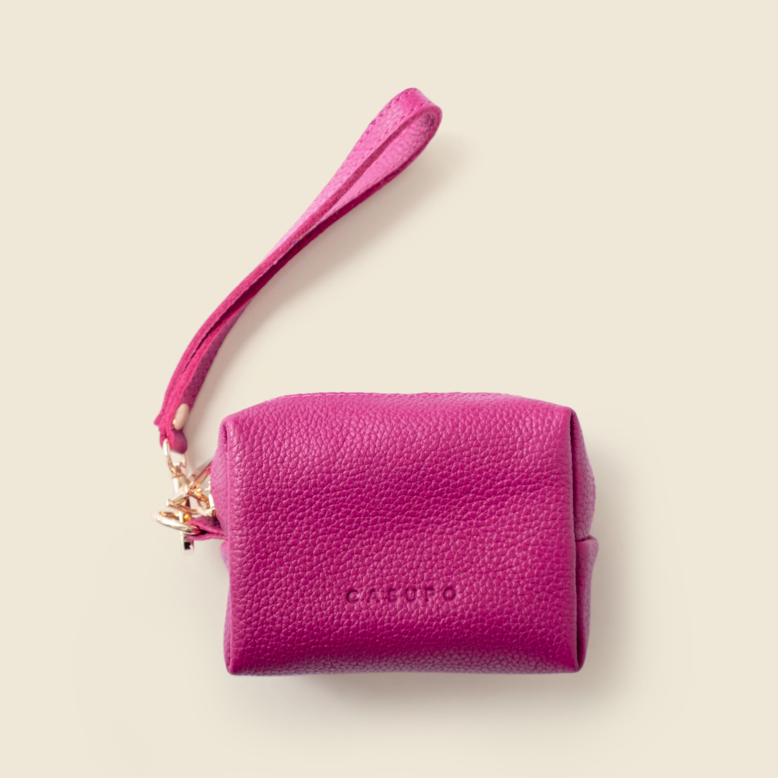 Pink leather pouch with a strap on a beige background