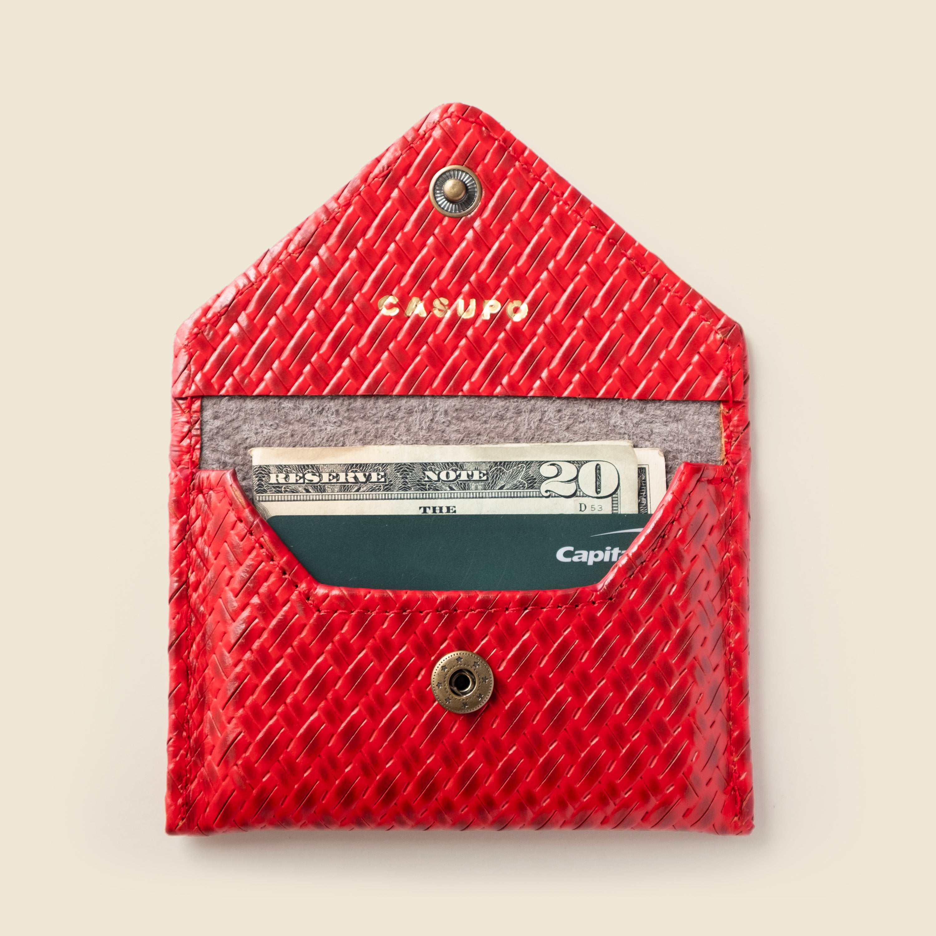 Red textured cardholder with money and cards on a beige background