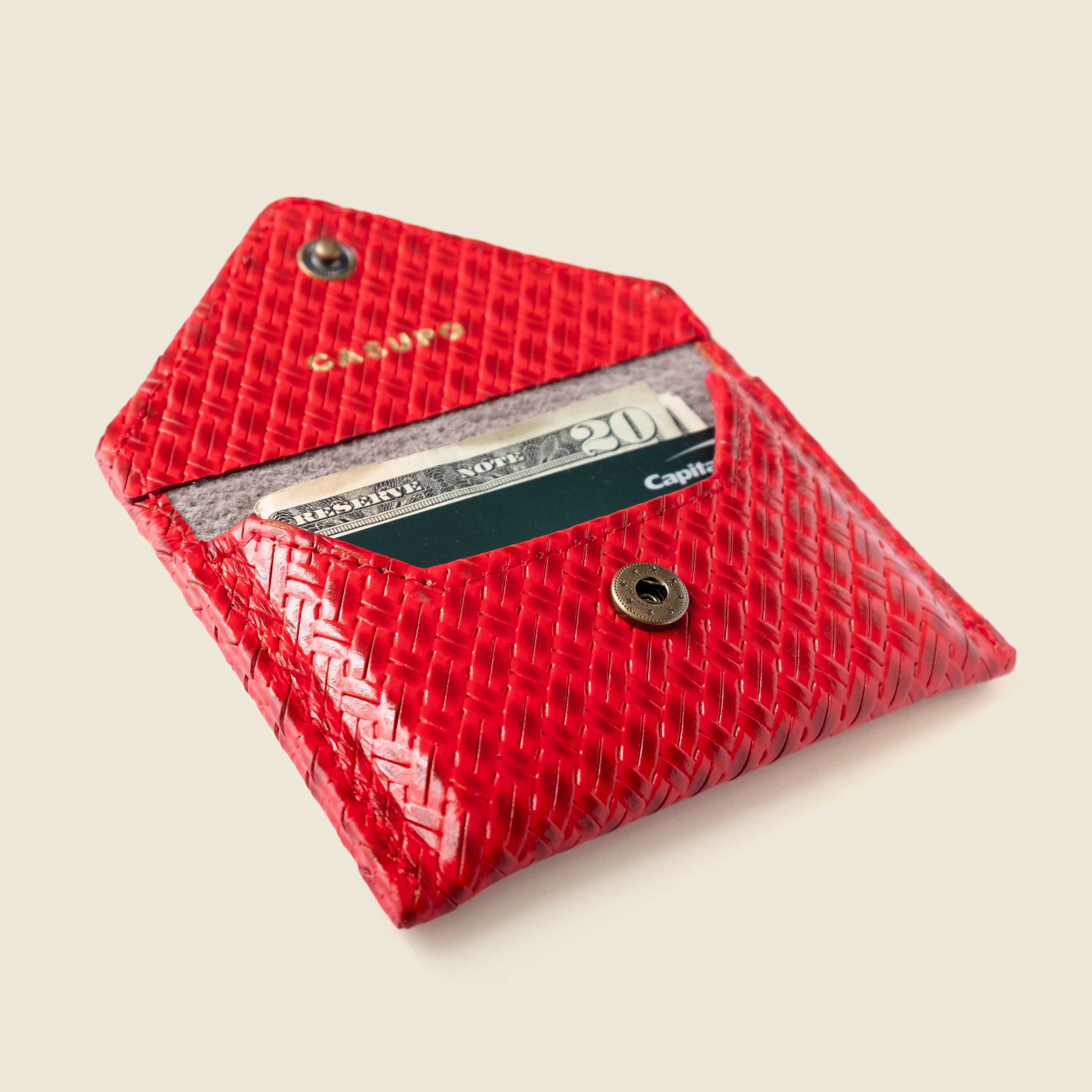 Red textured wallet with a card slot on a beige background