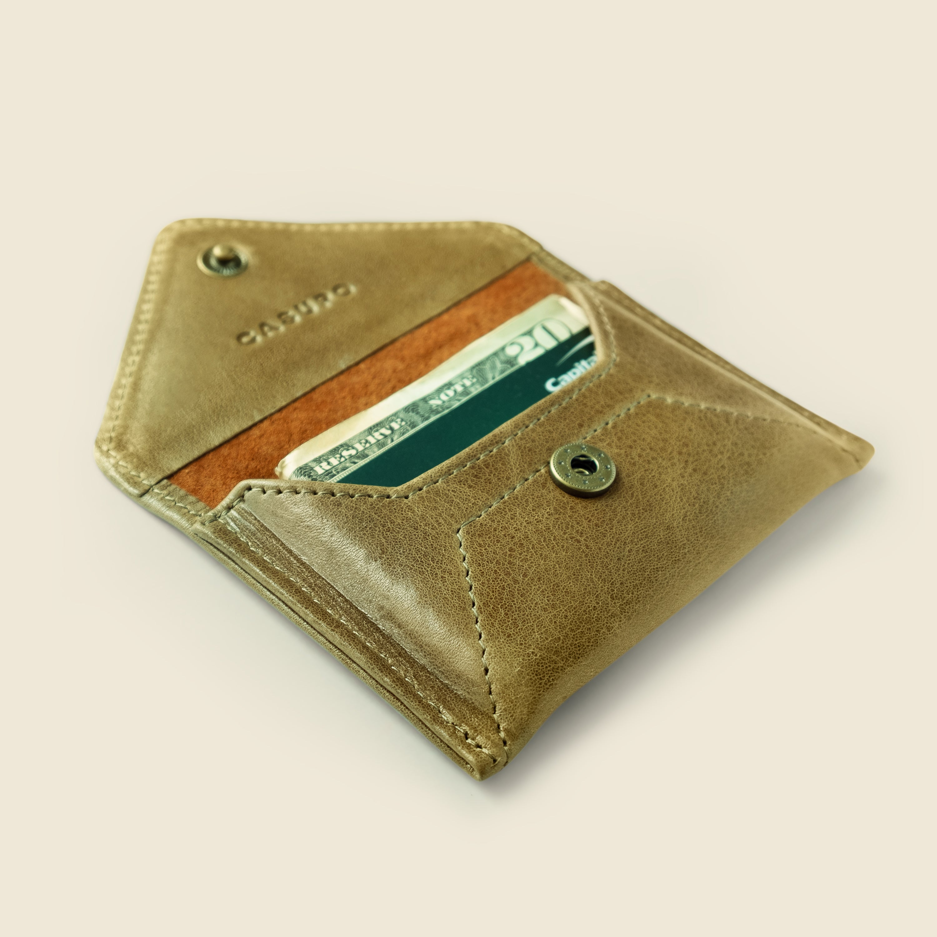 Brown leather wallet with a card inside on a beige background