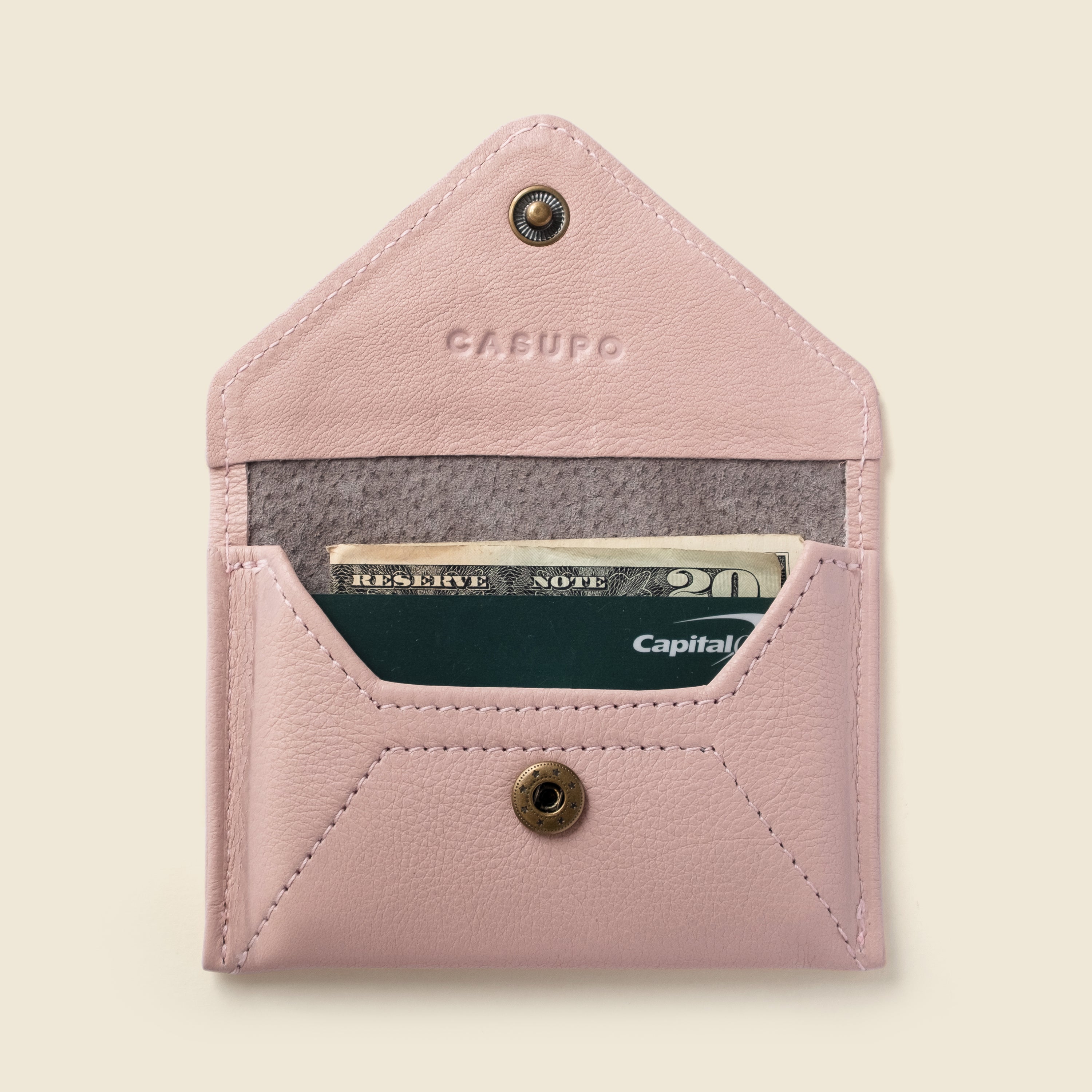 Pink leather wallet with a card inside on a beige background