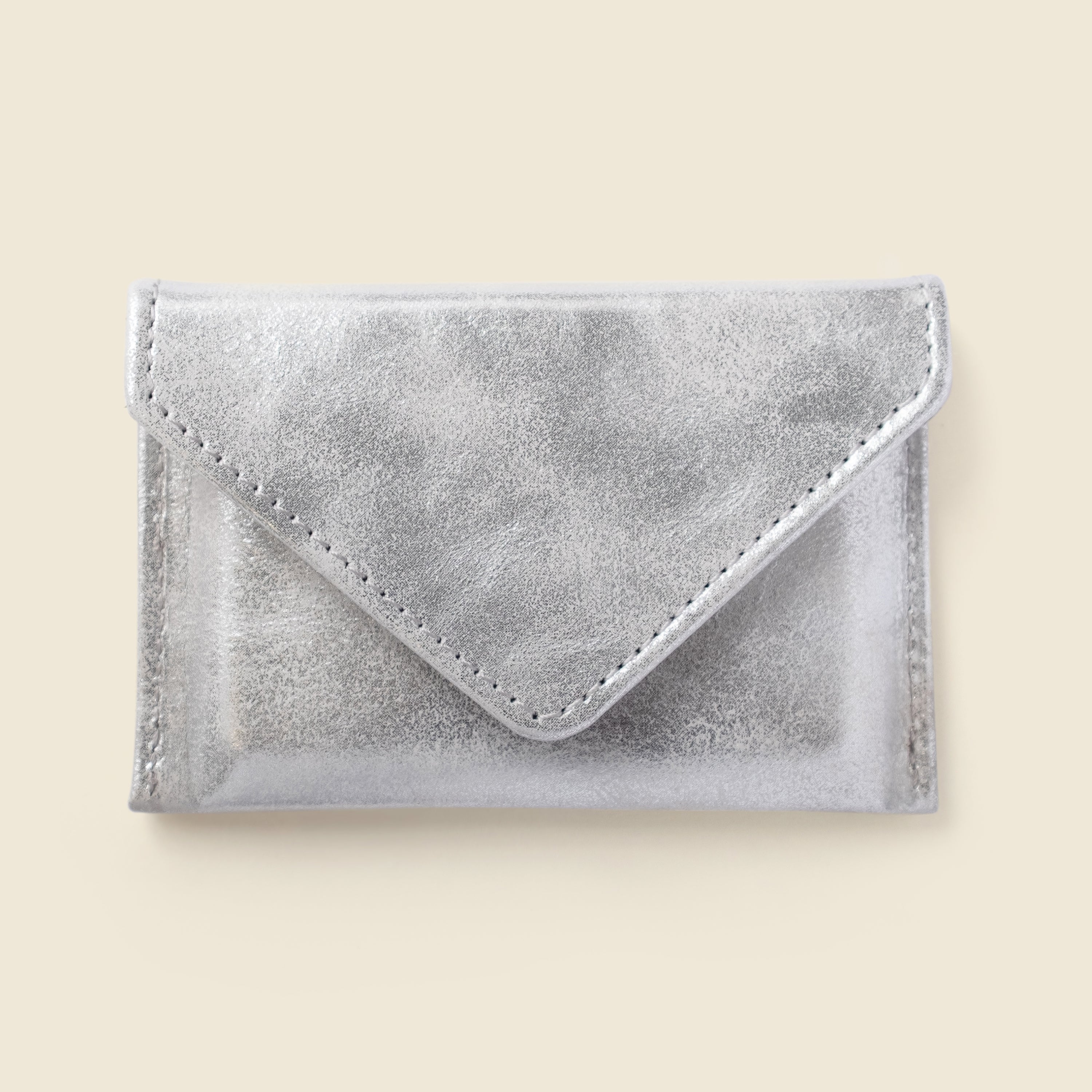Silver envelope-shaped cardholder on a beige background