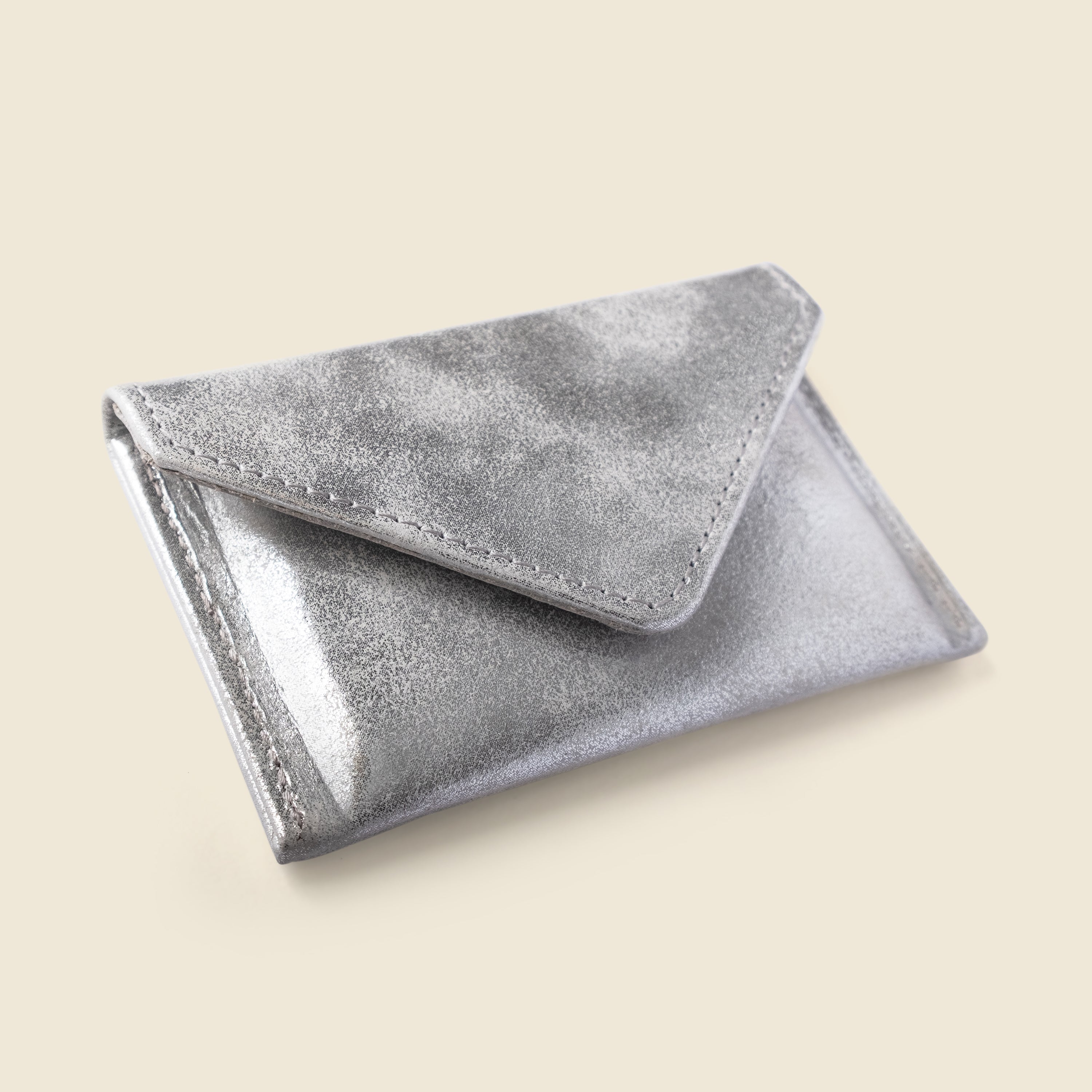 Silver metallic clutch on a beige background