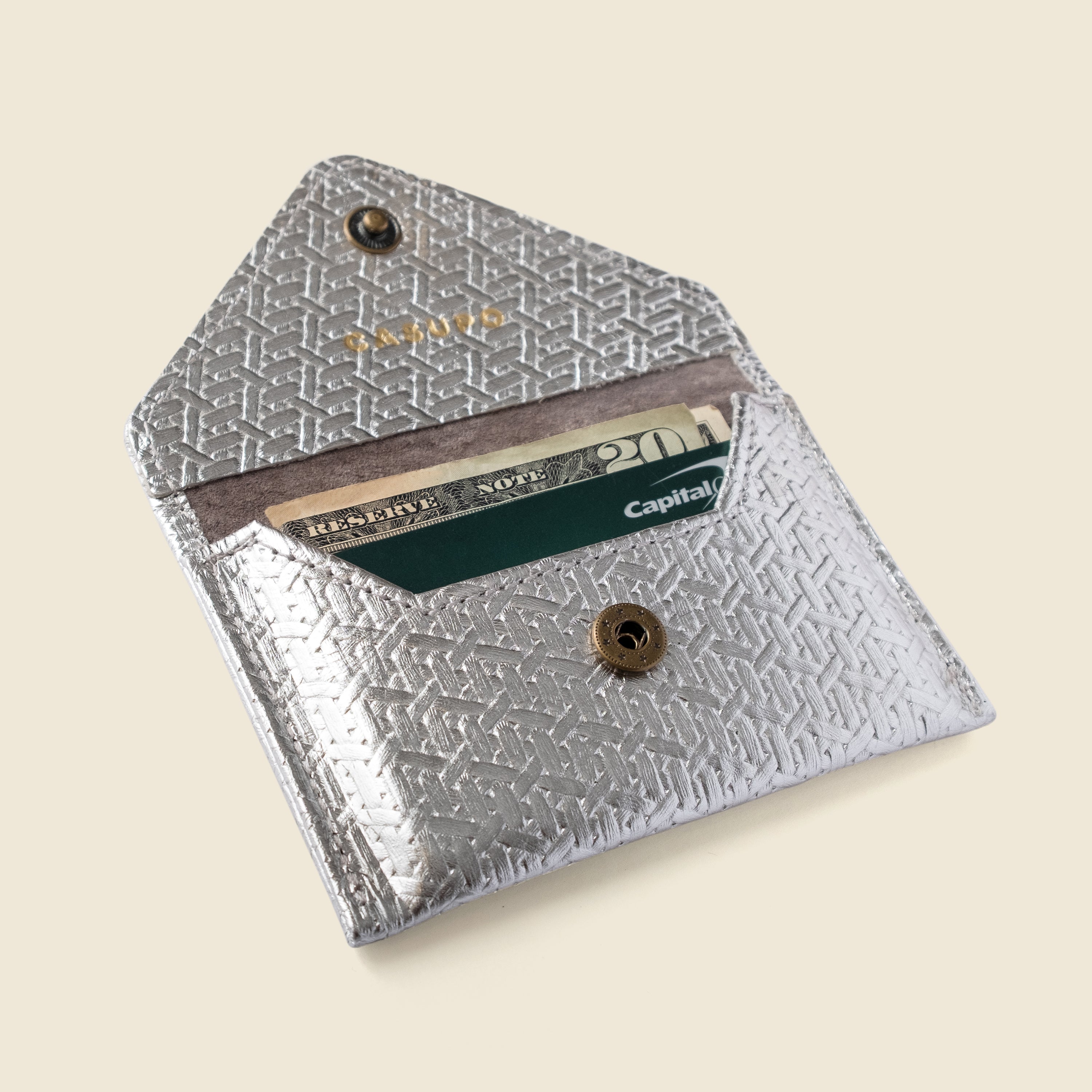 Silver cardholder with a card inside on a beige background