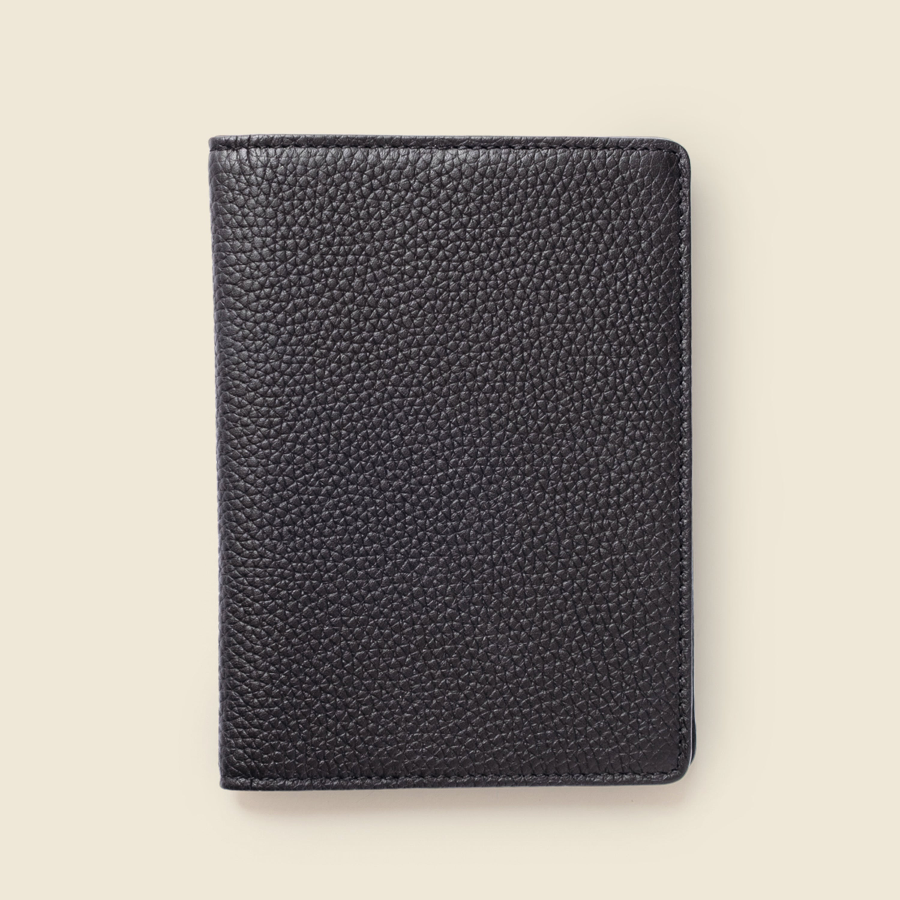 Black leather passport holder on a beige background