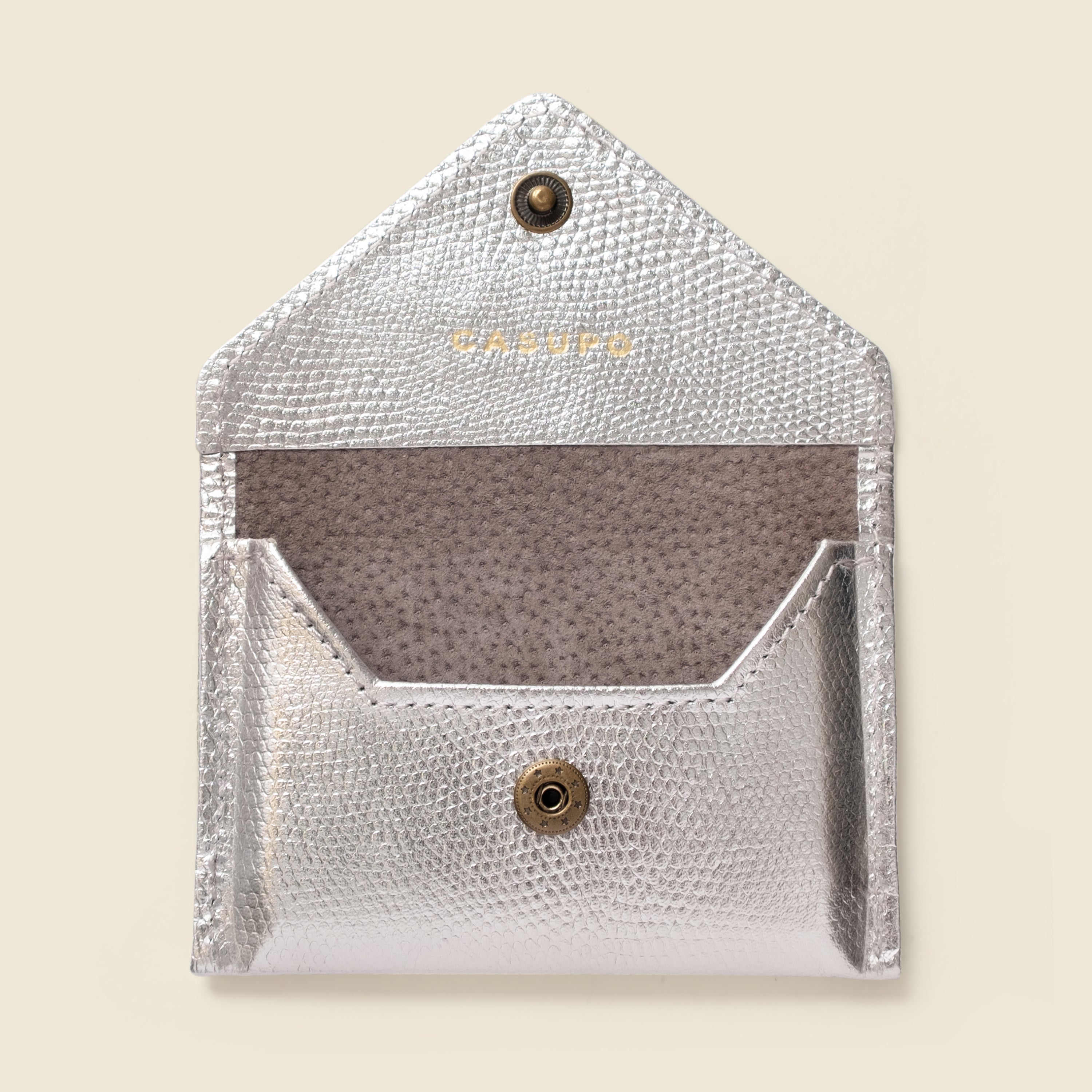 Silver textured cardholder with brand logo on a beige background