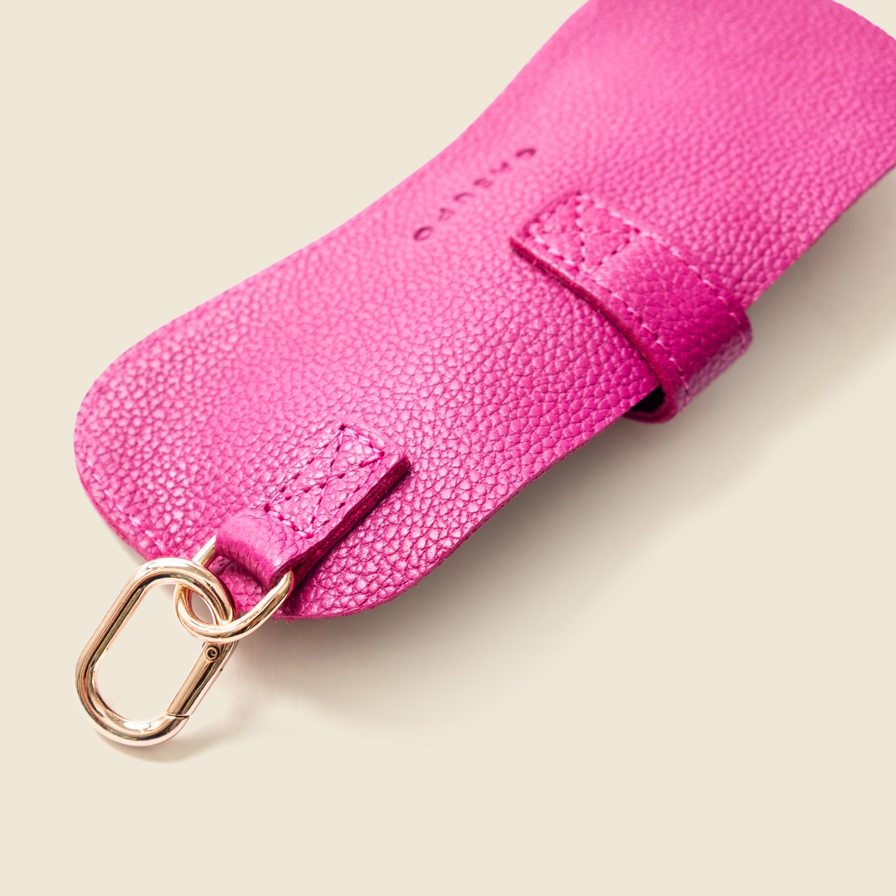 Close-up of a pink leather strap with a gold buckle on a white background
