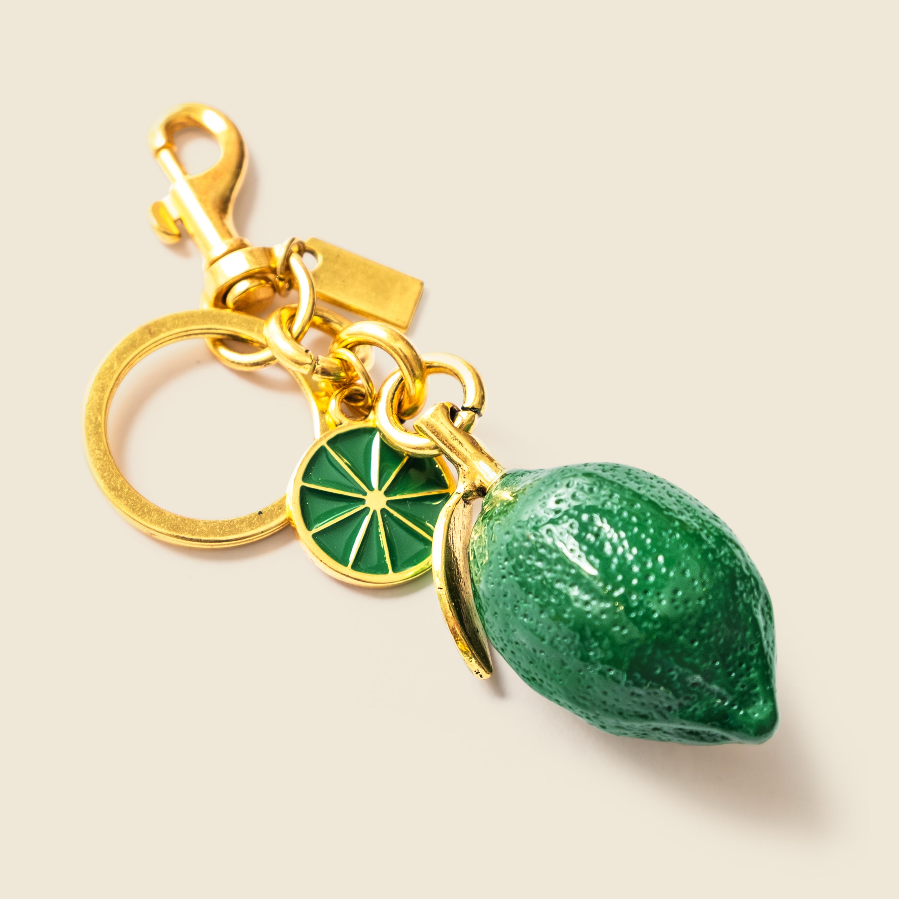 Keychain with green lemon and gold accents on a beige background
