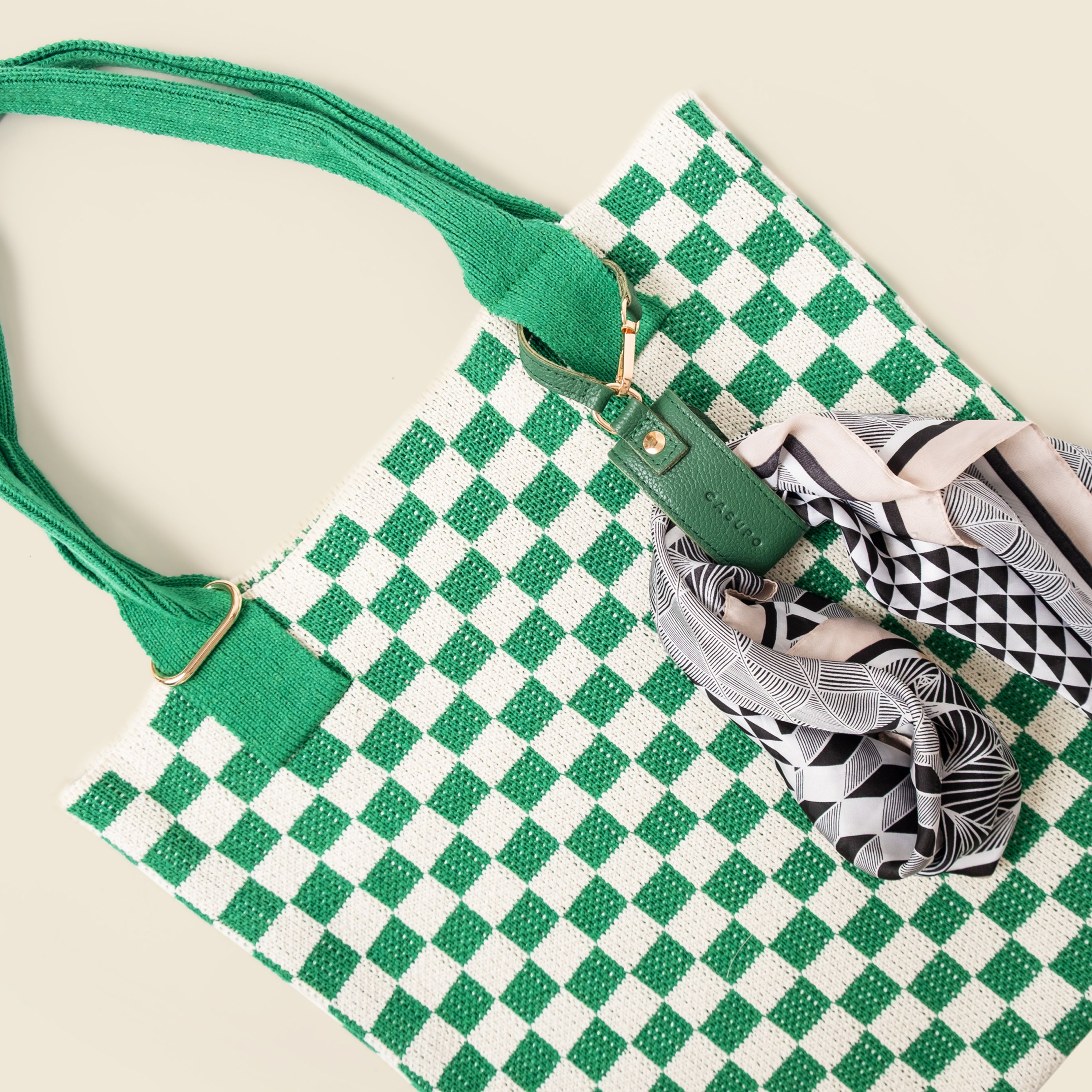 Green and white checkered bag with a strap on a beige background