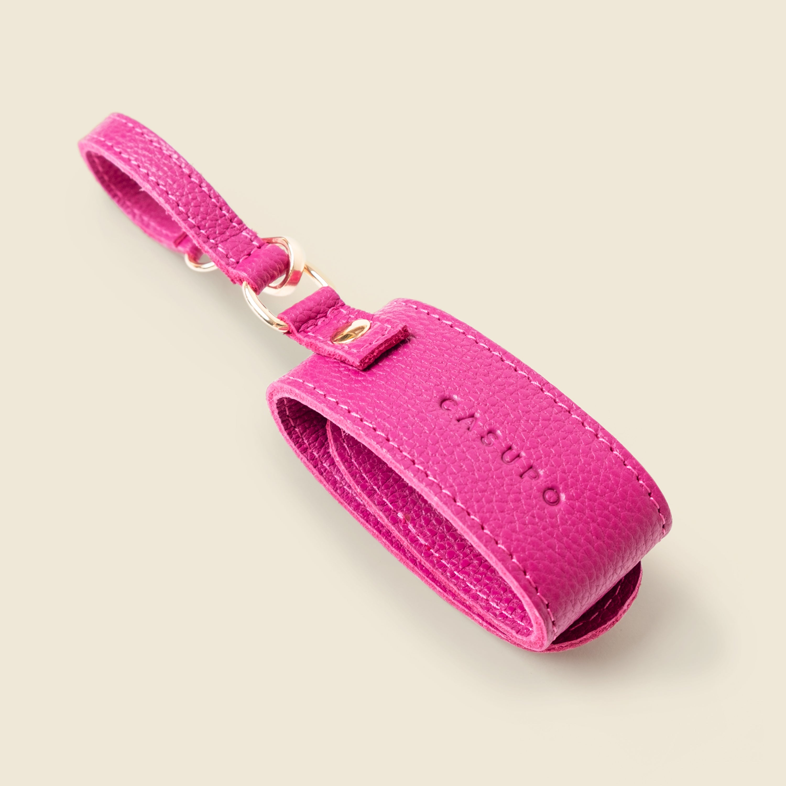 Pink leather luggage tag with CASUPO branding on a beige background