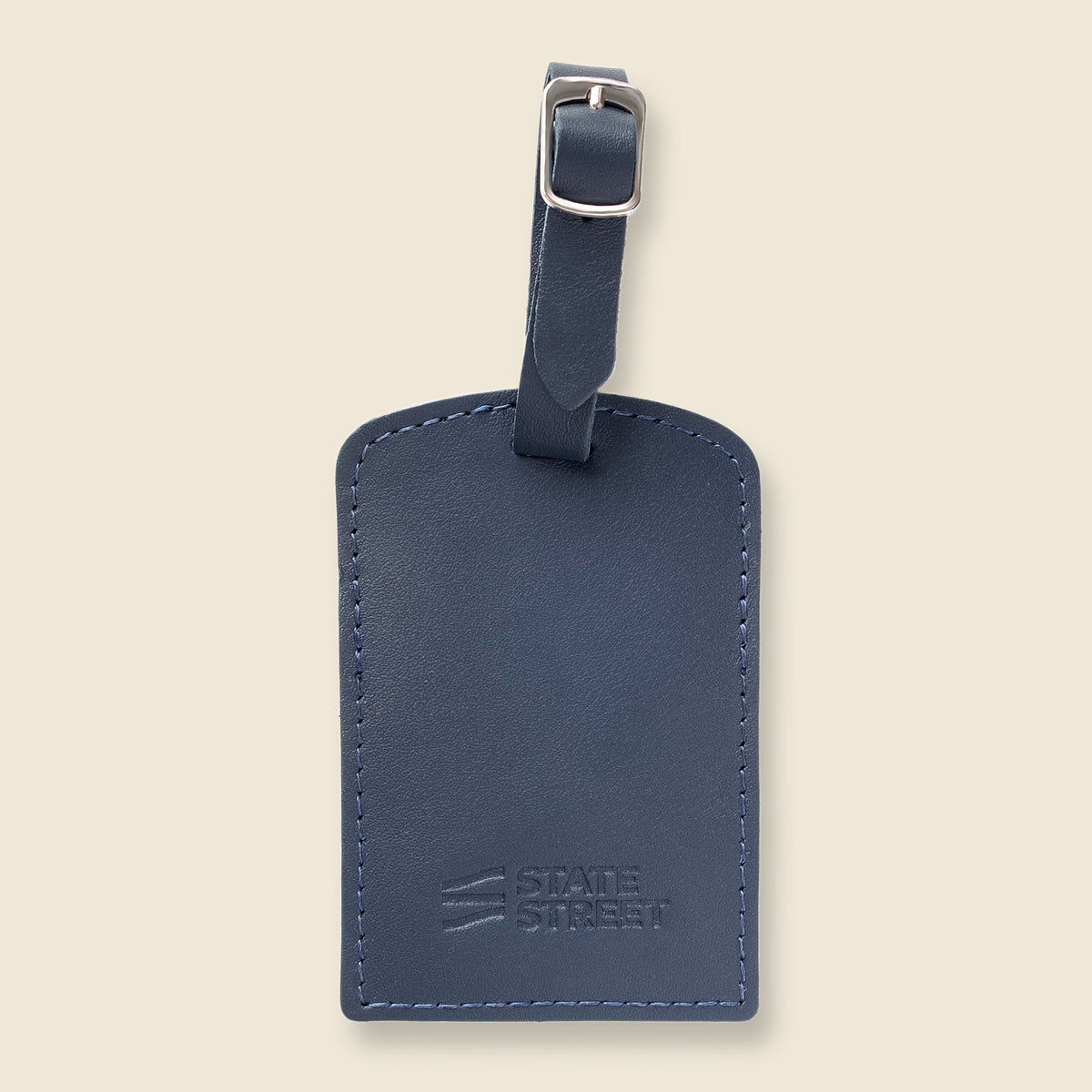 A navy blue leather luggage tag with a matching leather strap and silver buckle, featuring the embossed 'STATE STREET' logo on the bottom, set against a solid beige background.
