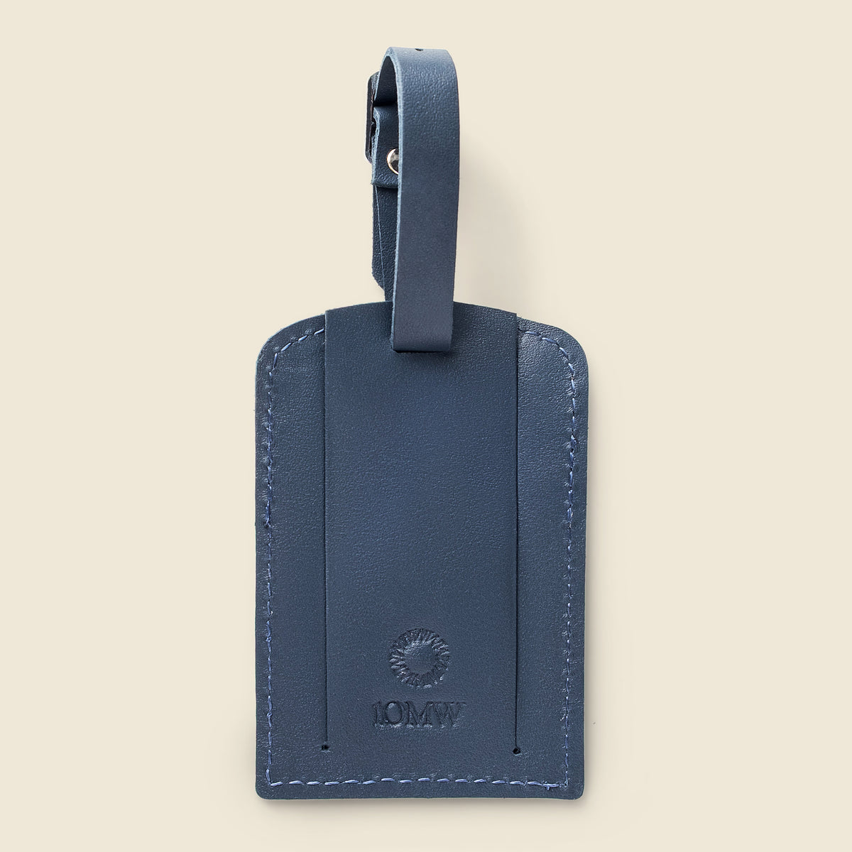 A navy blue leather luggage tag with a matching leather loop strap, featuring a debossed circular sunburst logo and the brand name '10MW' on a light beige background.
