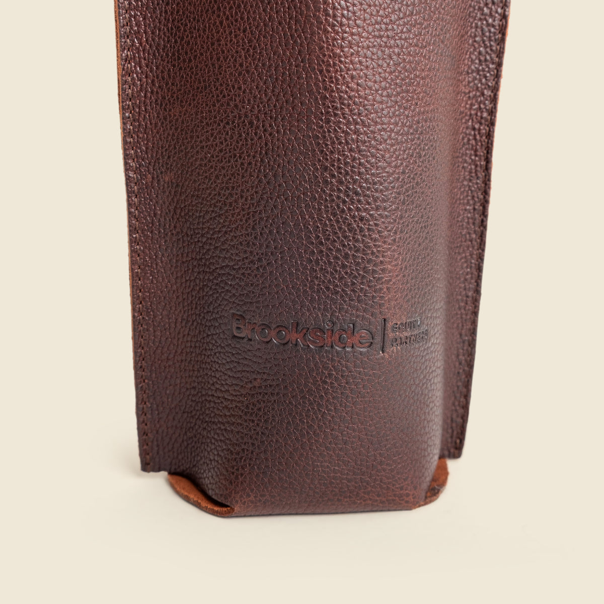 A close-up of a dark brown pebbled leather pouch or sleeve with the debossed brand name 'Brookside' visible on the front, set against a plain off-white background.