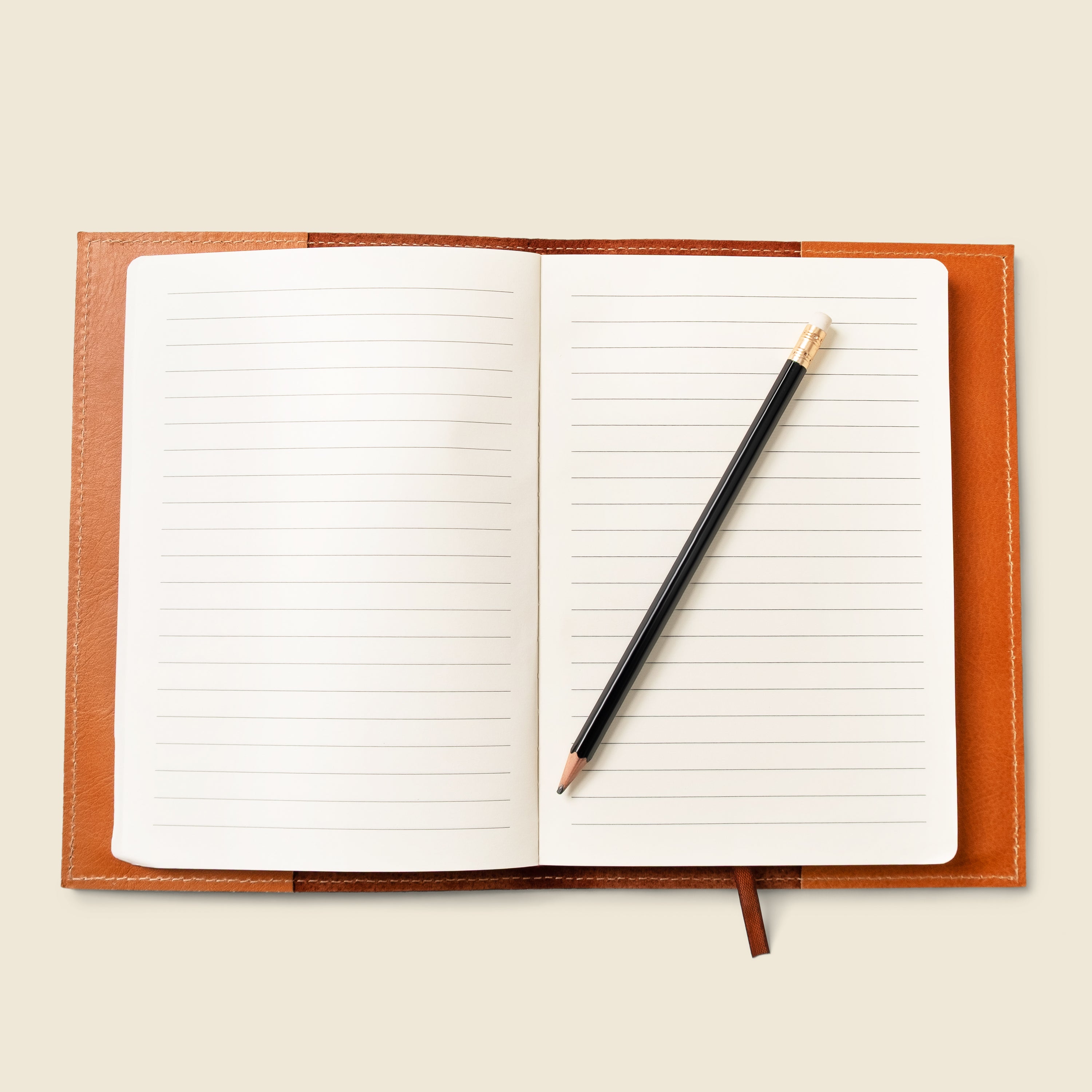 Open notebook with a pencil on a beige background
