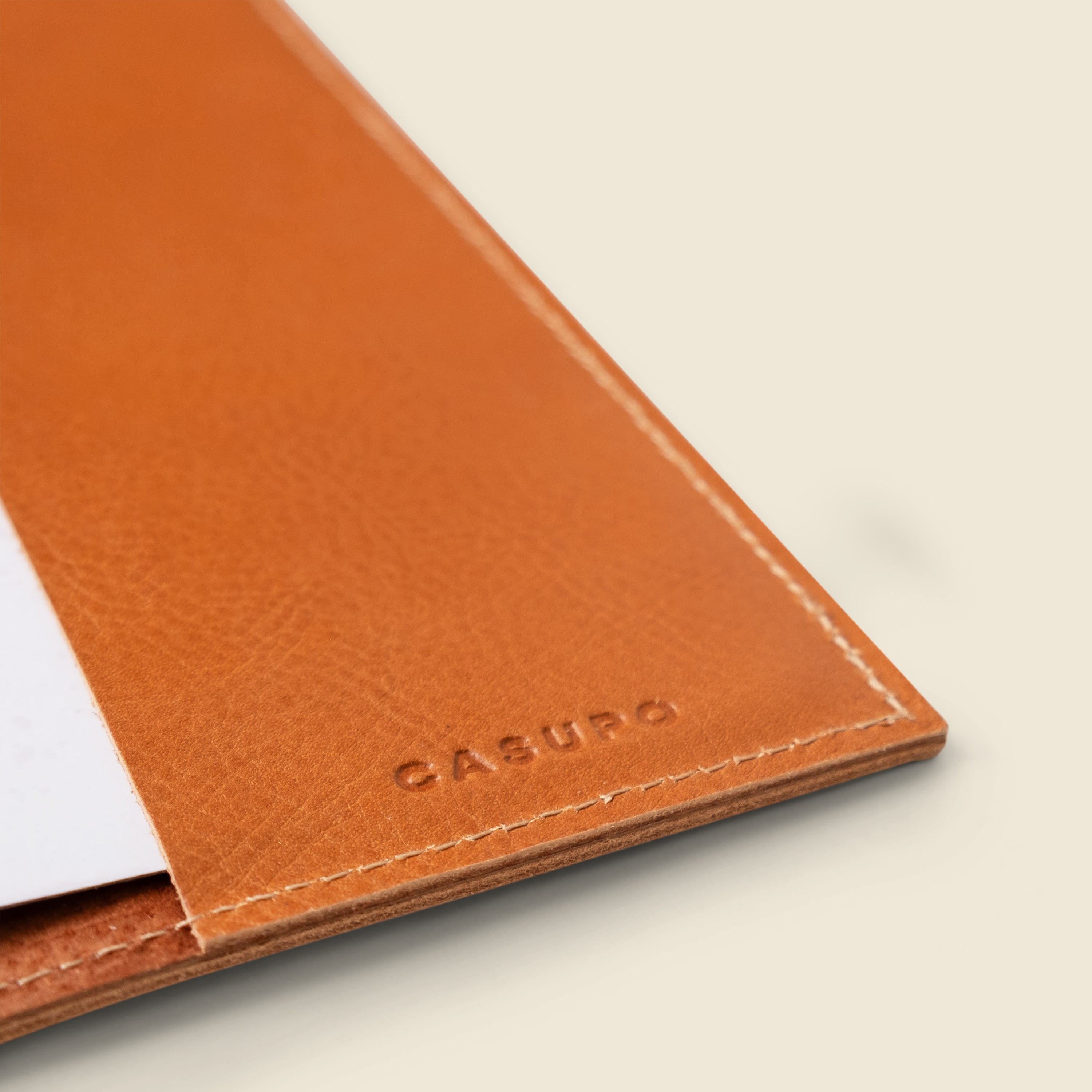 Close-up of a brown leather wallet with 'CASUPO' branding on a light background