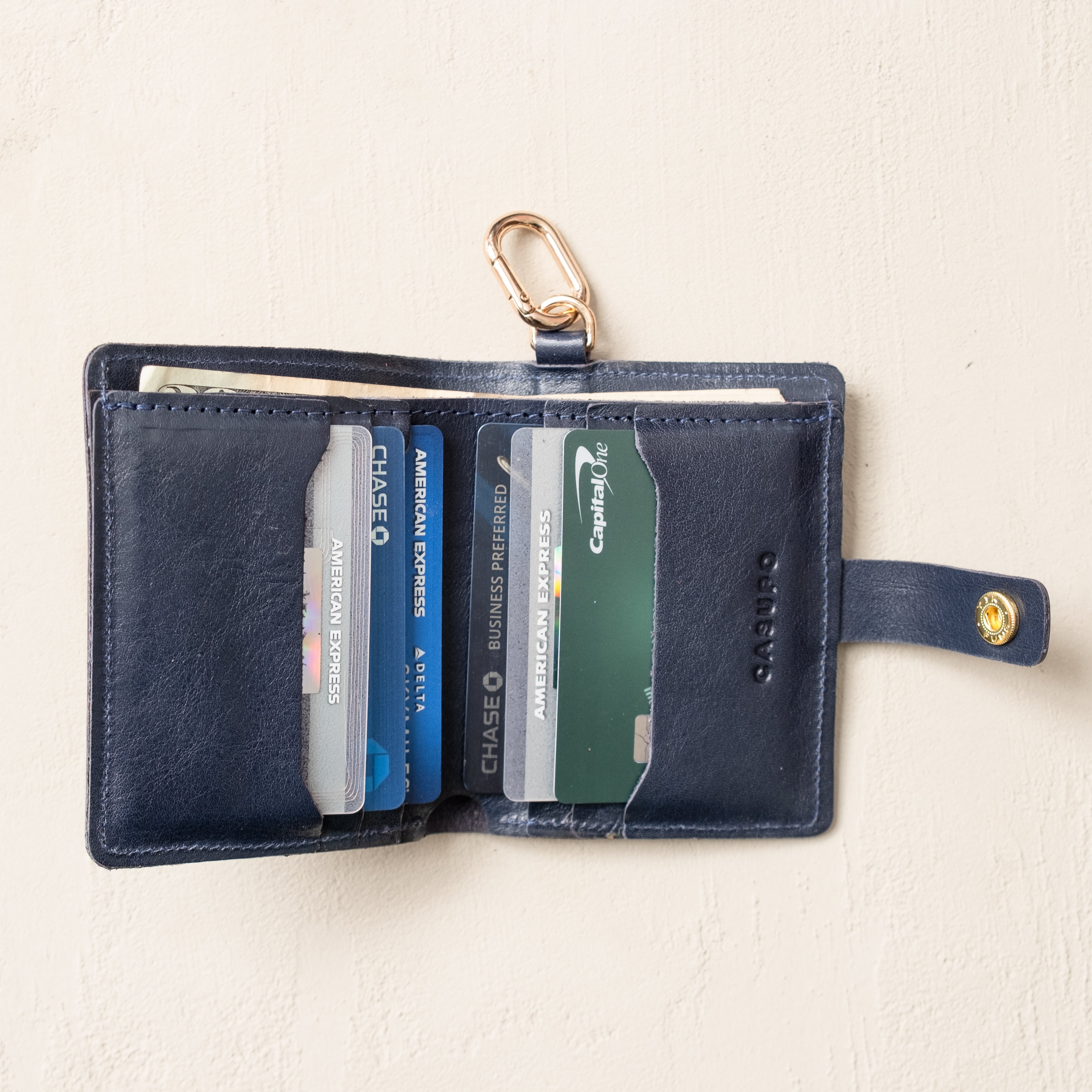 Close-up of snap closure on marine blue leather wallet with key ring