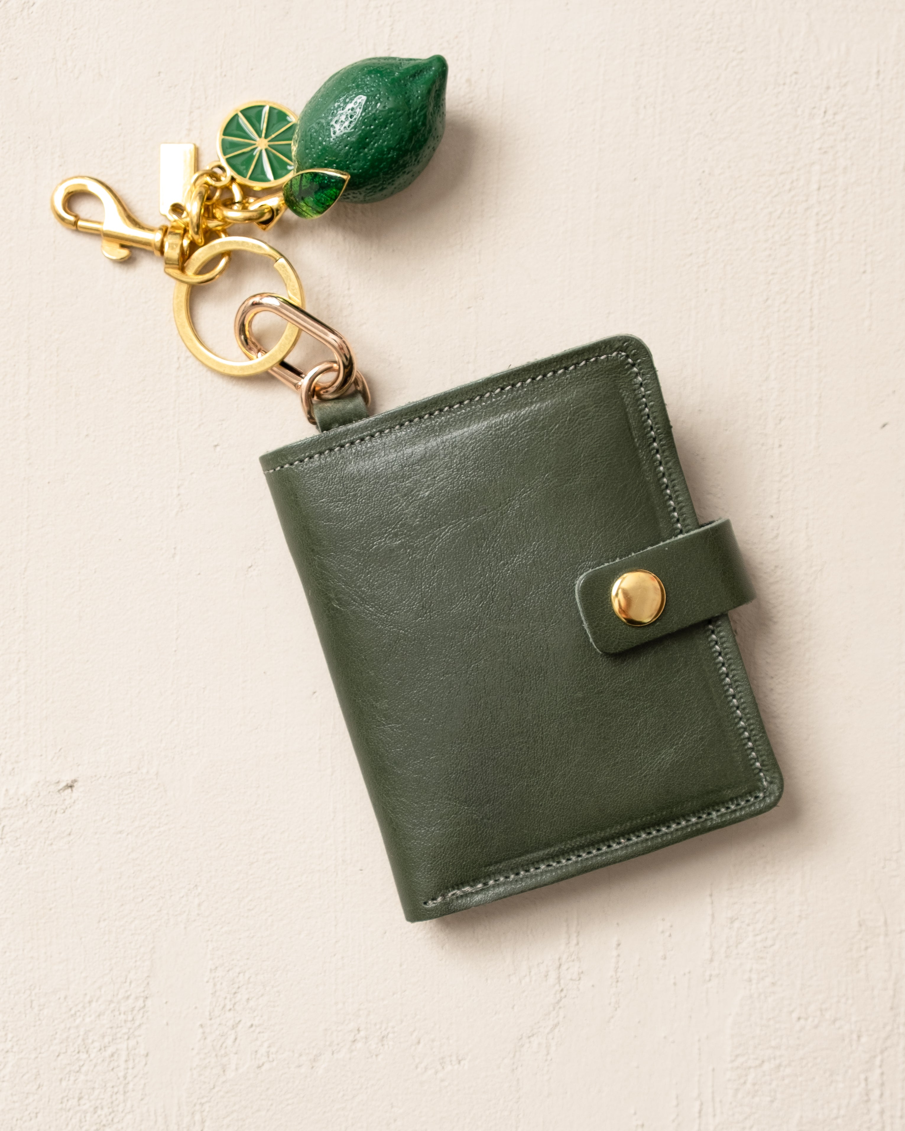 Green leather wallet with keychain on a beige background