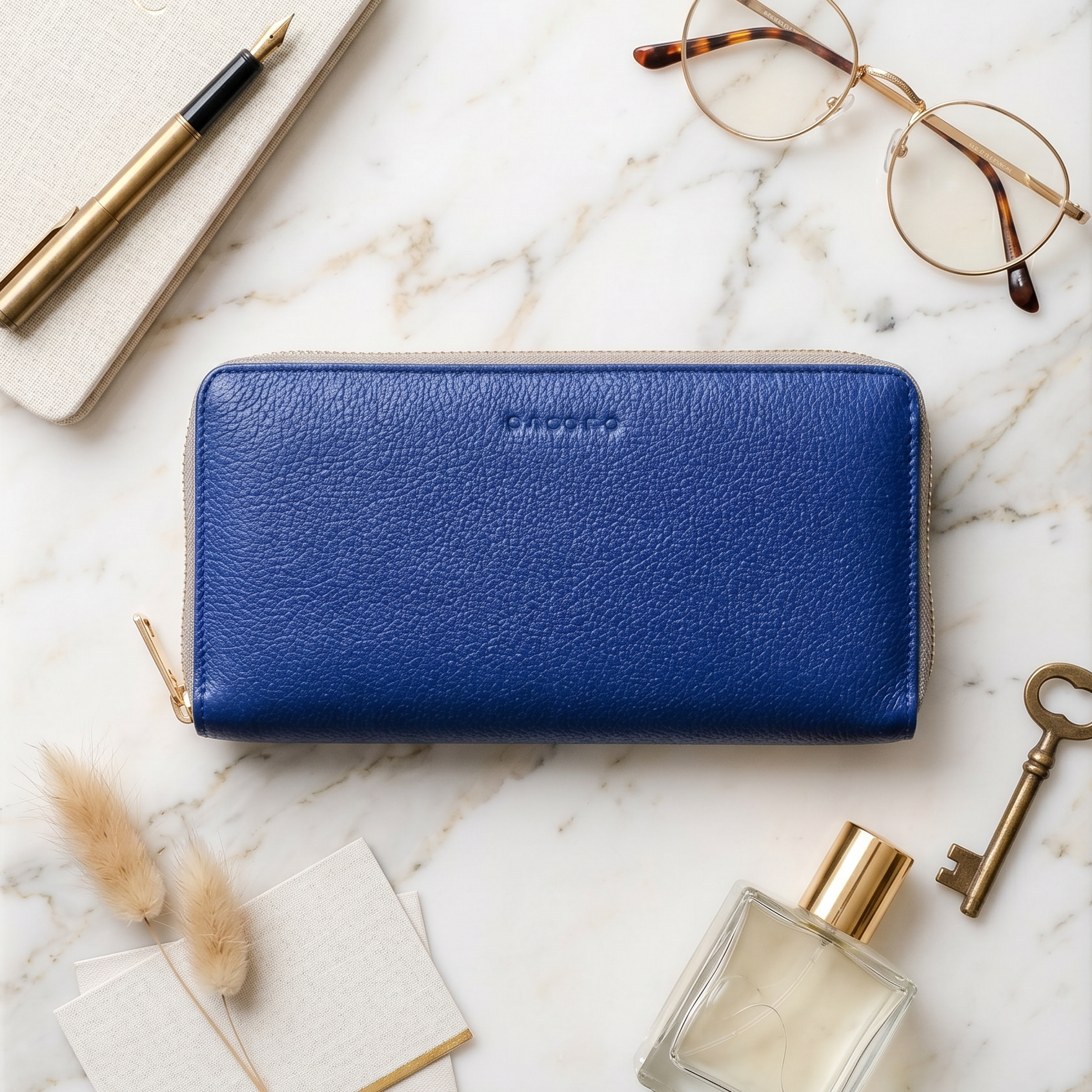 Blue wallet on a marble surface with glasses, pen, key, and perfume bottle.