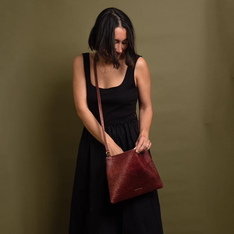 Happy woman holding a red gold leather crossbody bag