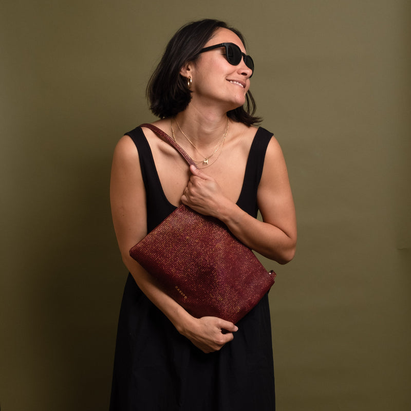 Happy woman holding a burgundy gold leather crossbody bag