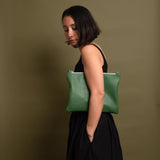 Woman wearing green leather bag under her arm. Using the bag without a strap