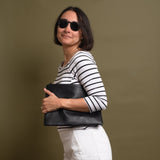 Woman showing her black leather crossbody bag under her arm