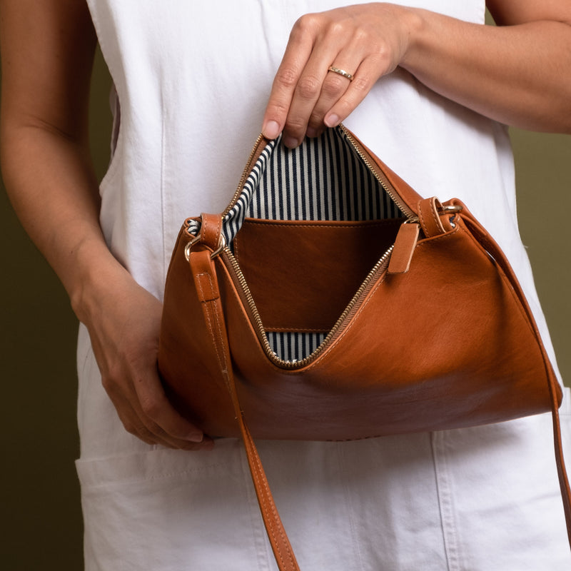 Brown leather crossbody bag with white and navy striped cotton lining