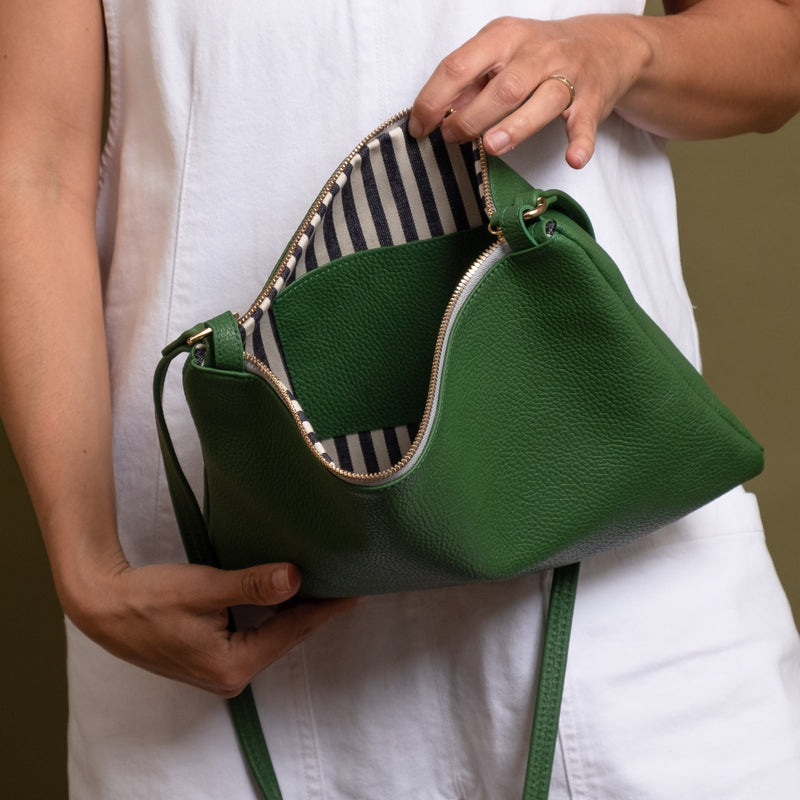 Green leather crossbody bag open with white and blue striped cotton lining