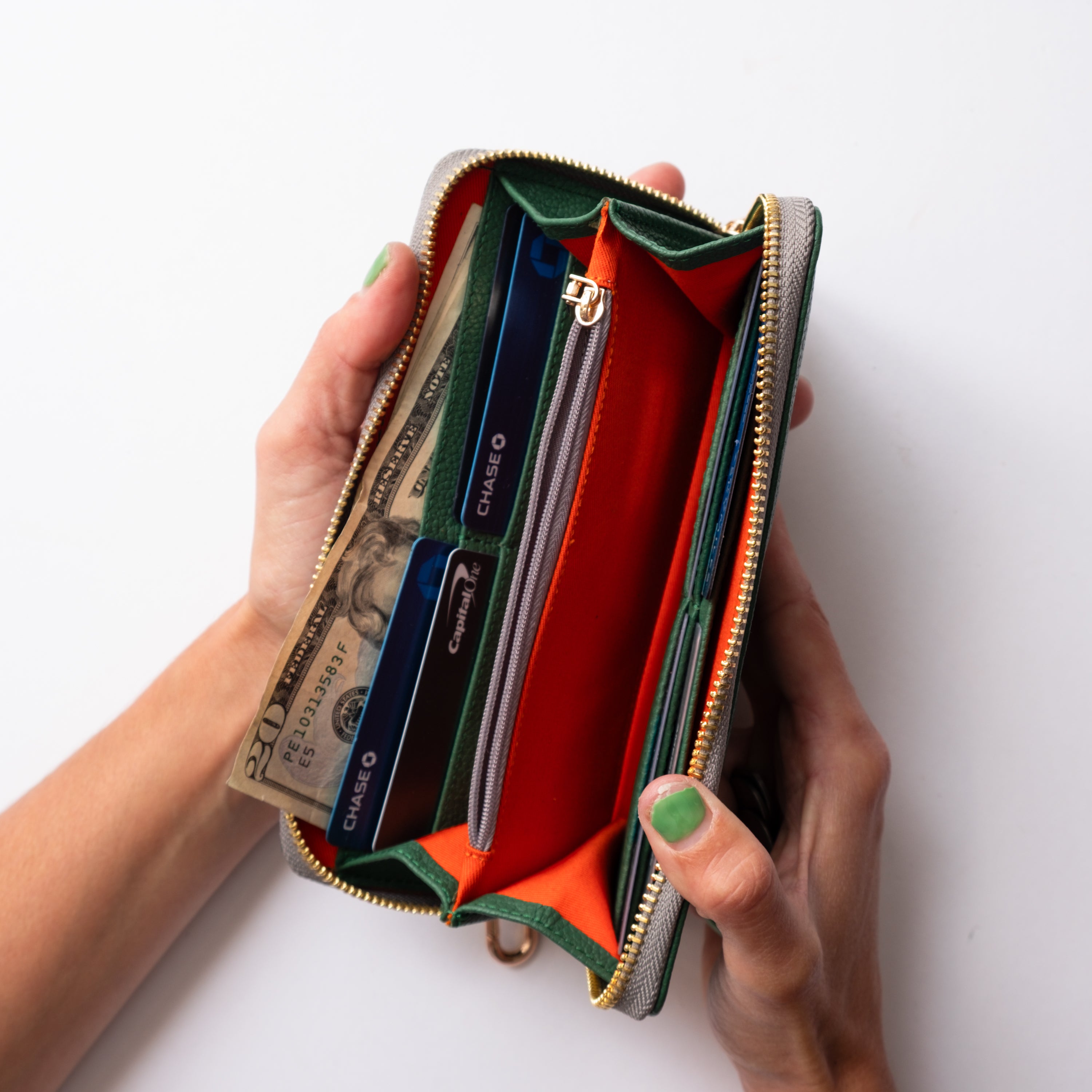 Hand holding an open wallet with money and cards on a white background