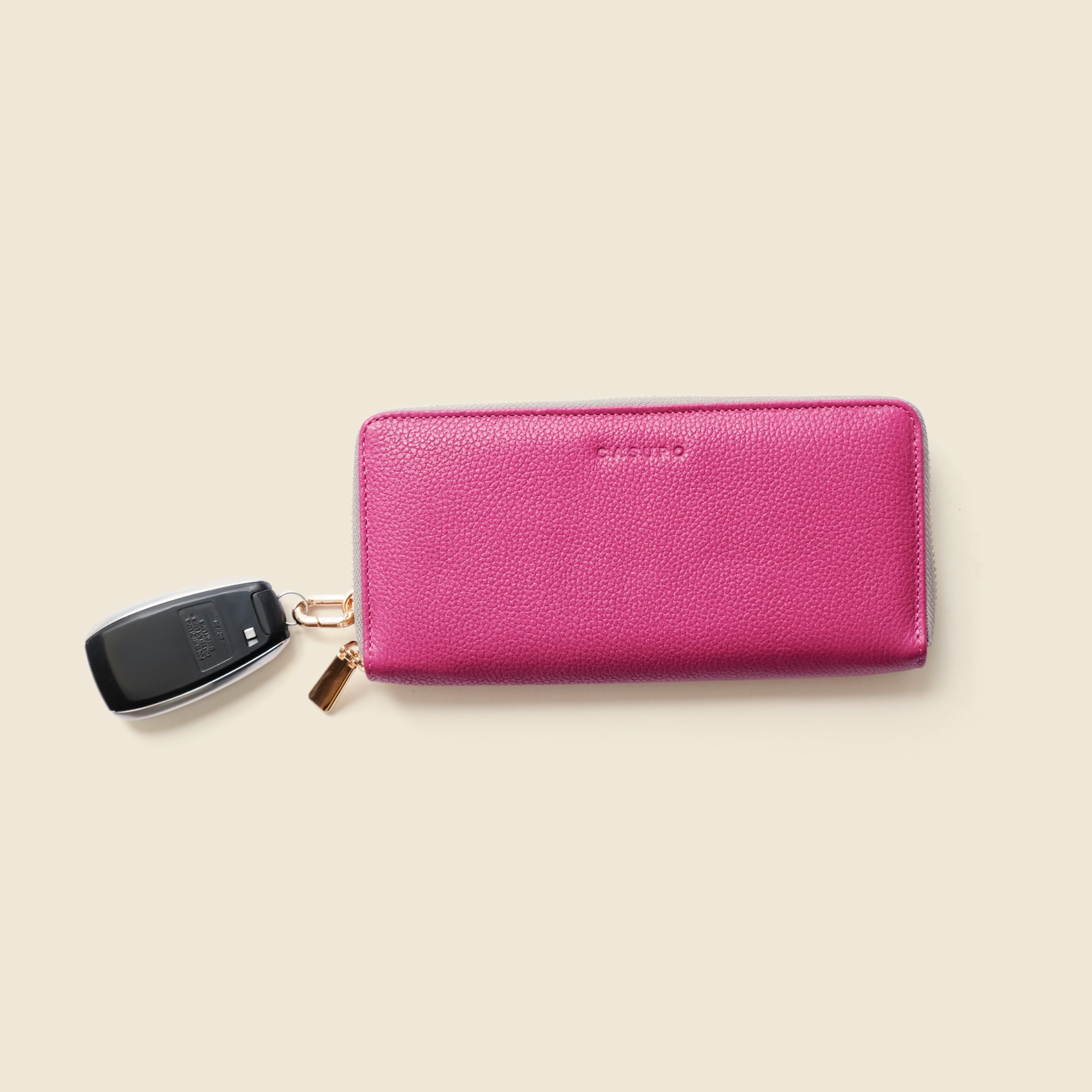 Pink wallet with a keychain on a beige background