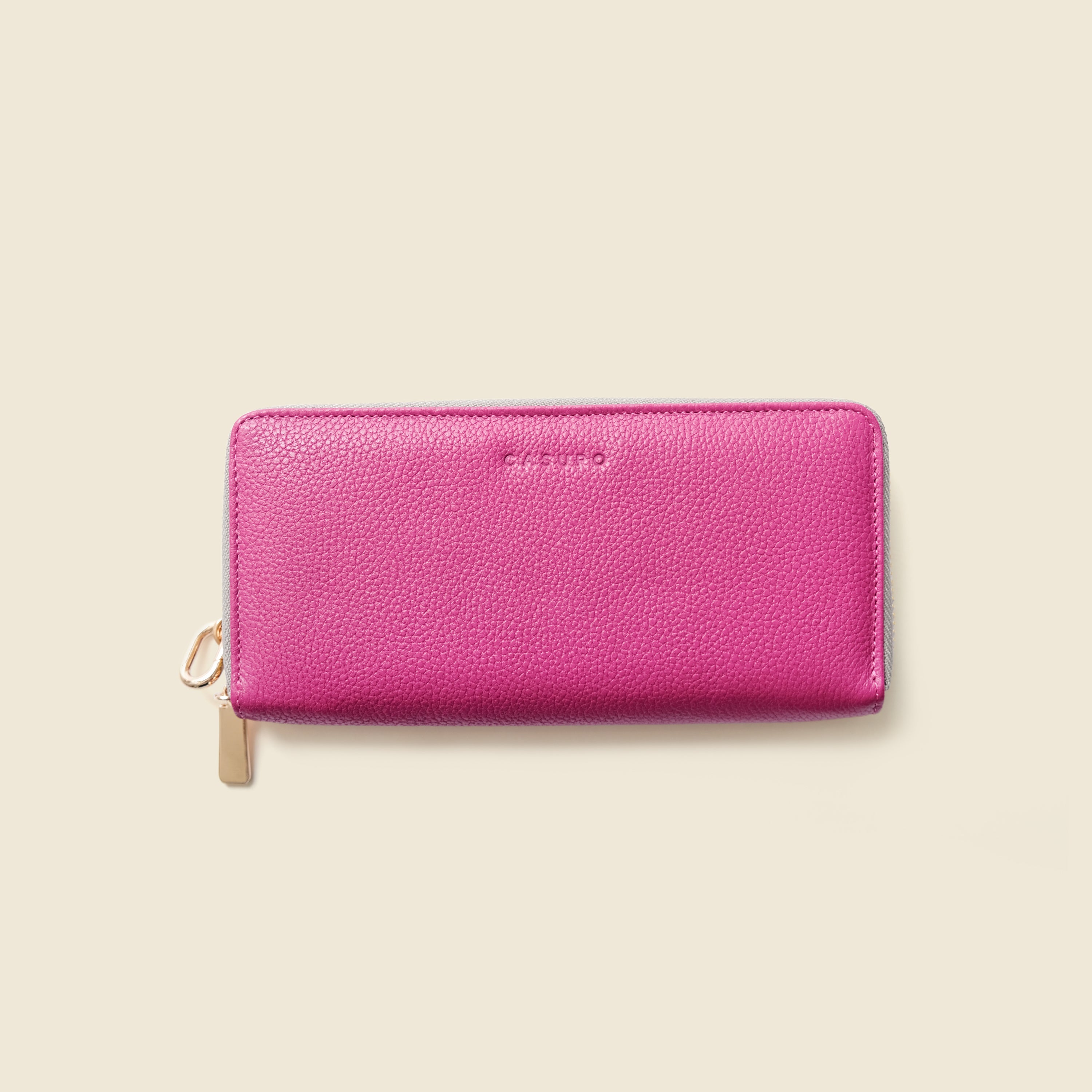 Pink wallet with gold zipper on a beige background