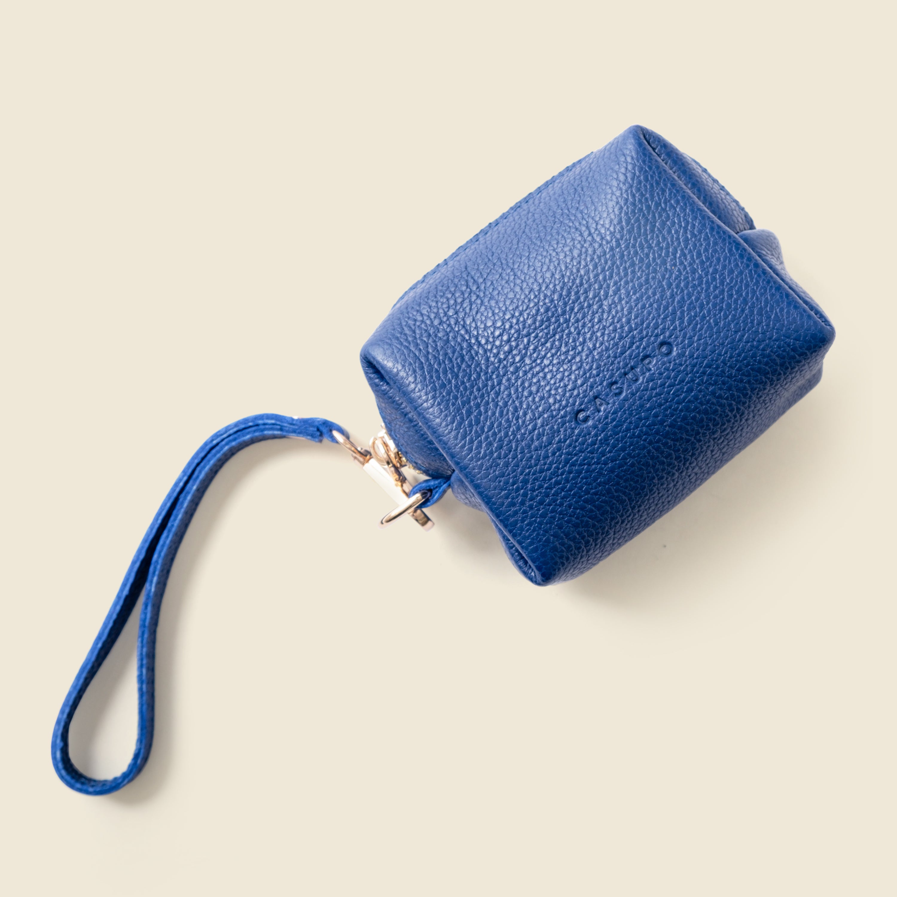 Blue leather wristlet on a beige background