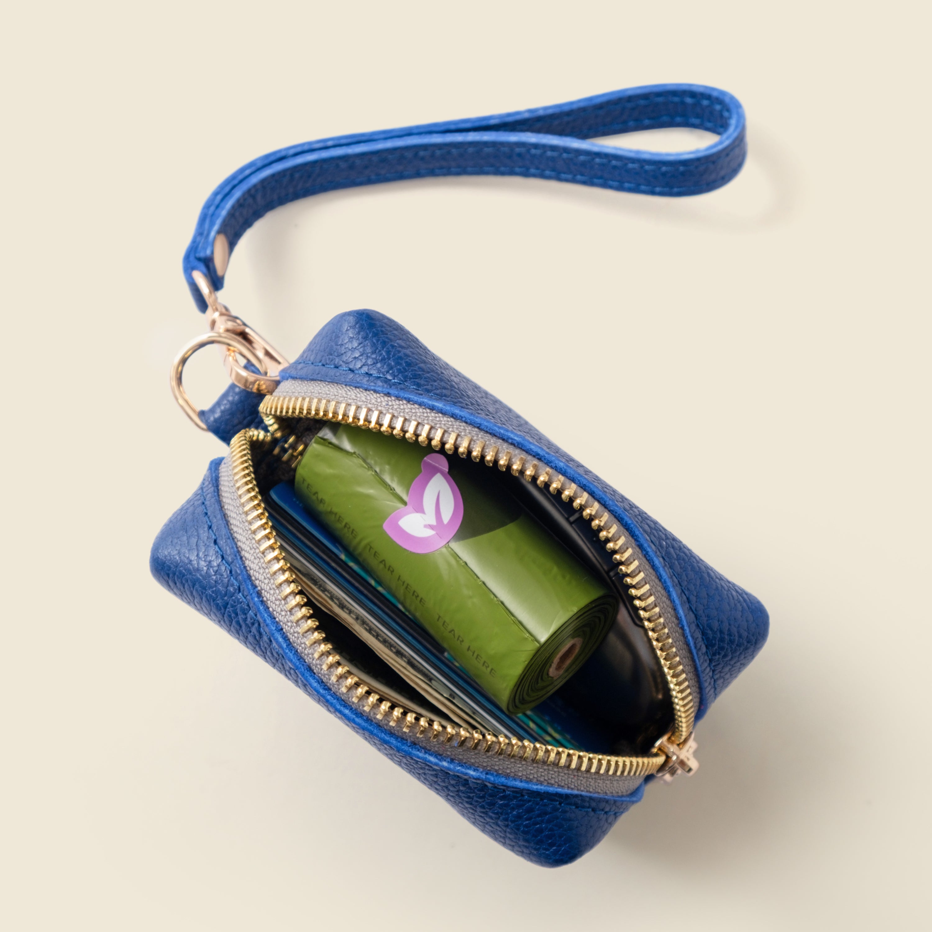 Blue leather pouch with a zipper, containing a green item with a pink logo on a beige background