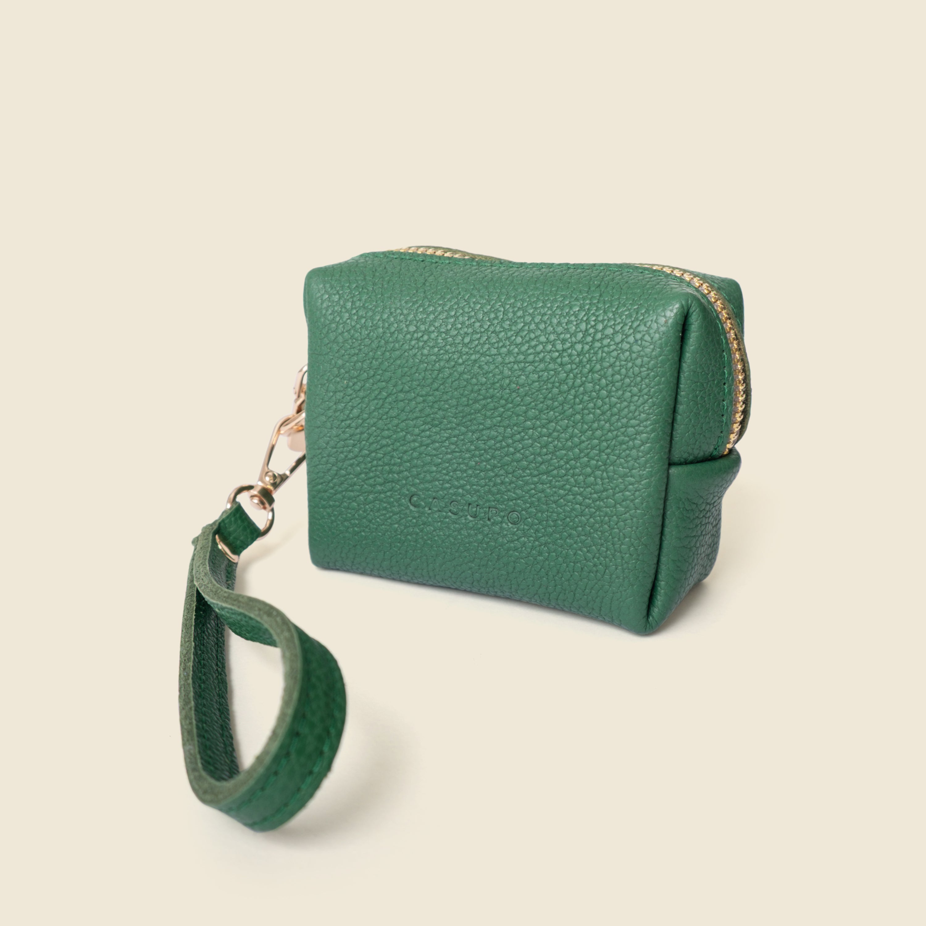 Green leather pouch with a strap on a beige background
