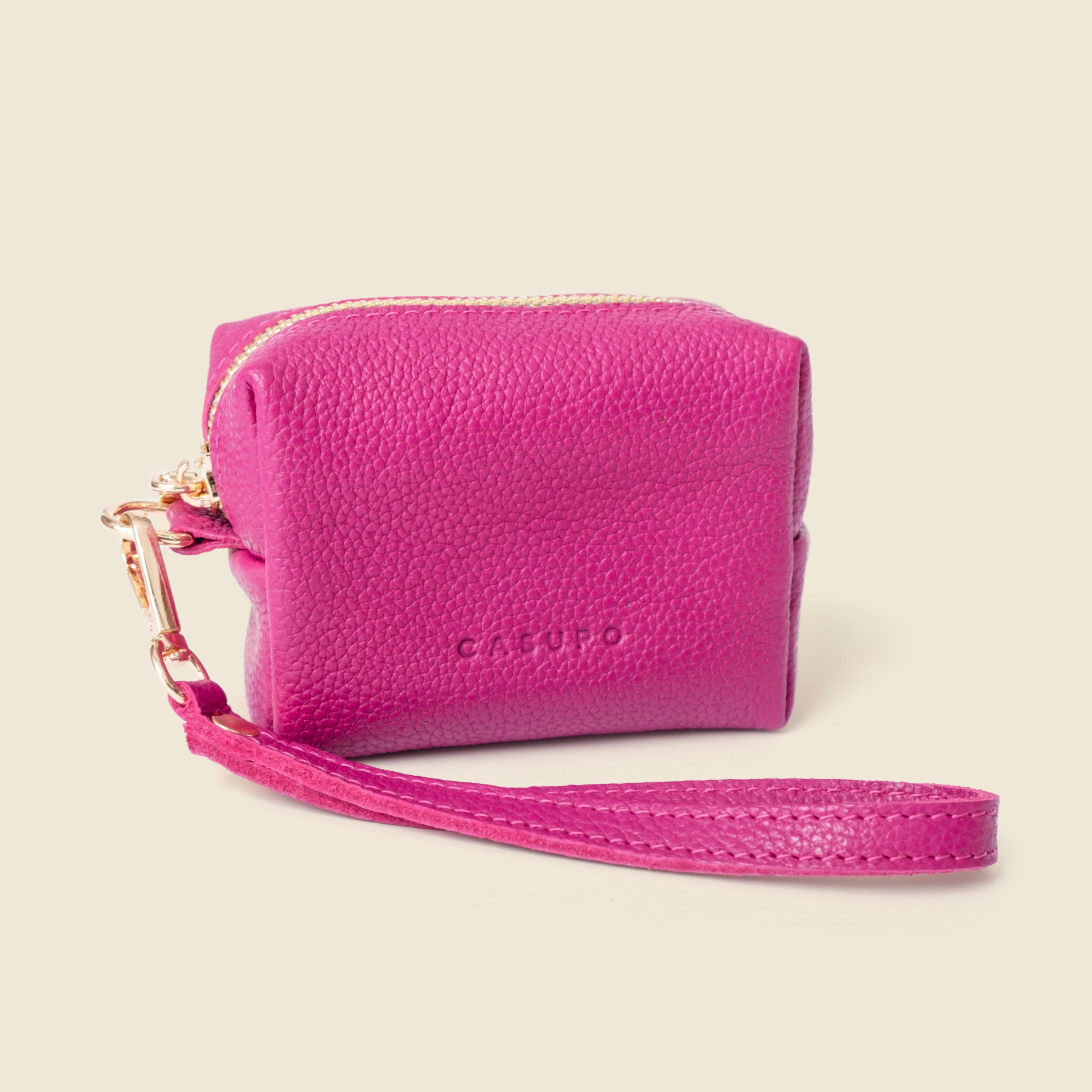 Pink leather wallet with wrist strap on a beige background