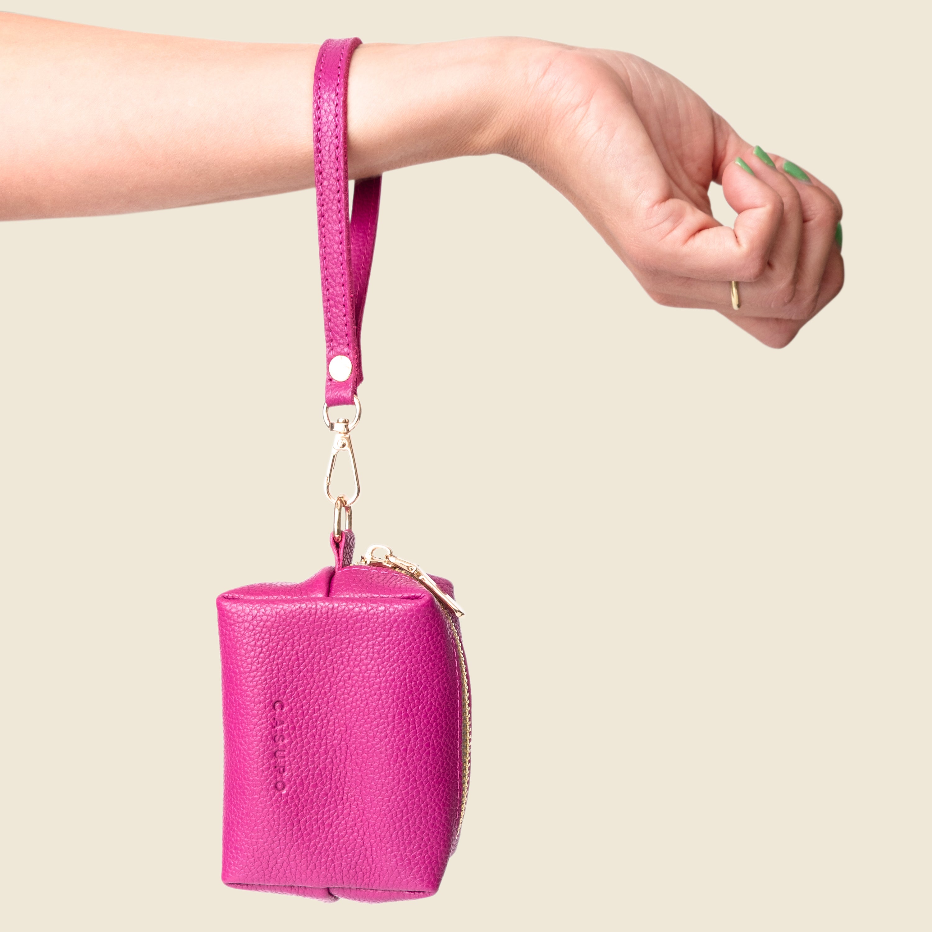 Pink keychain pouch held by a hand against a beige background