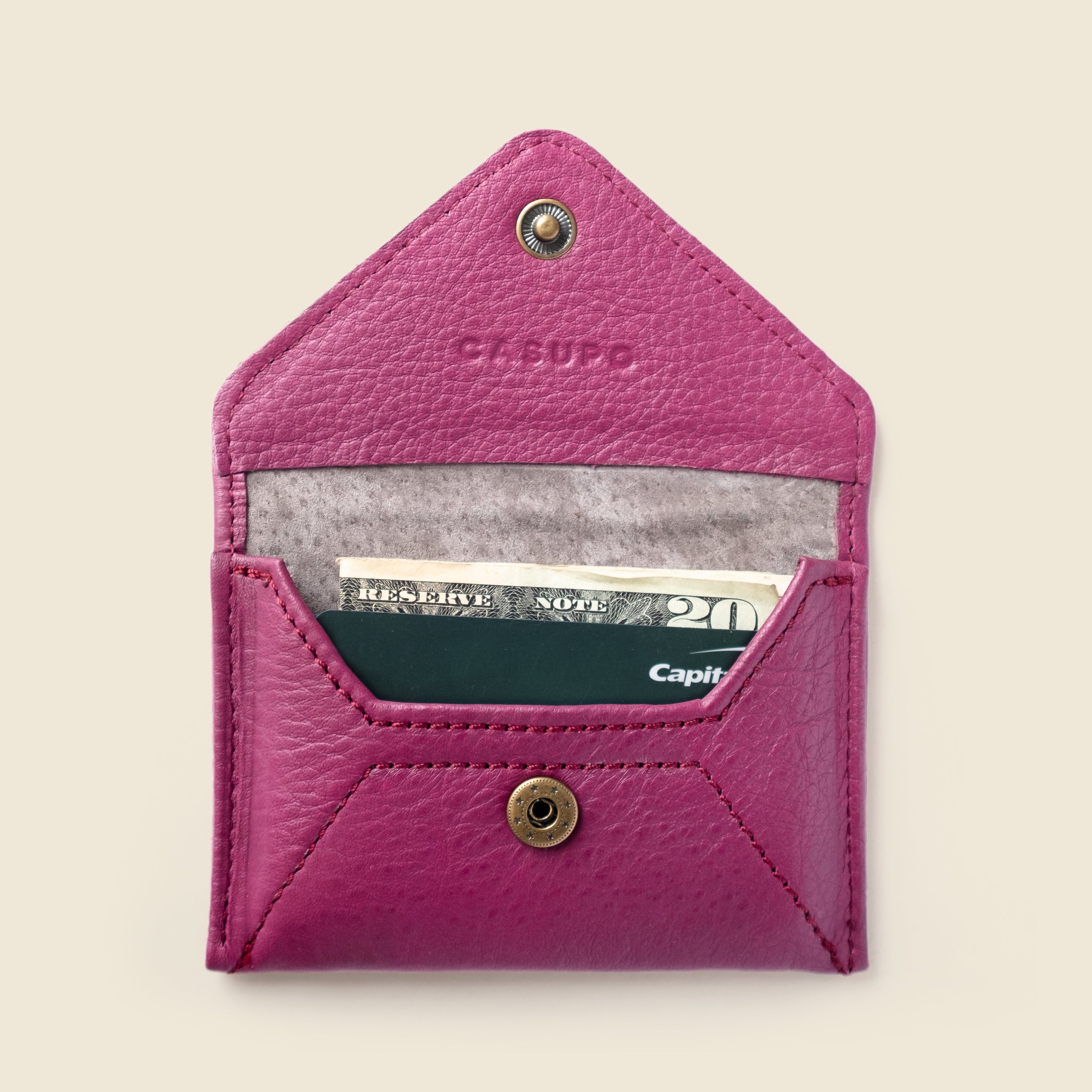 Pink leather wallet with money and card on a beige background