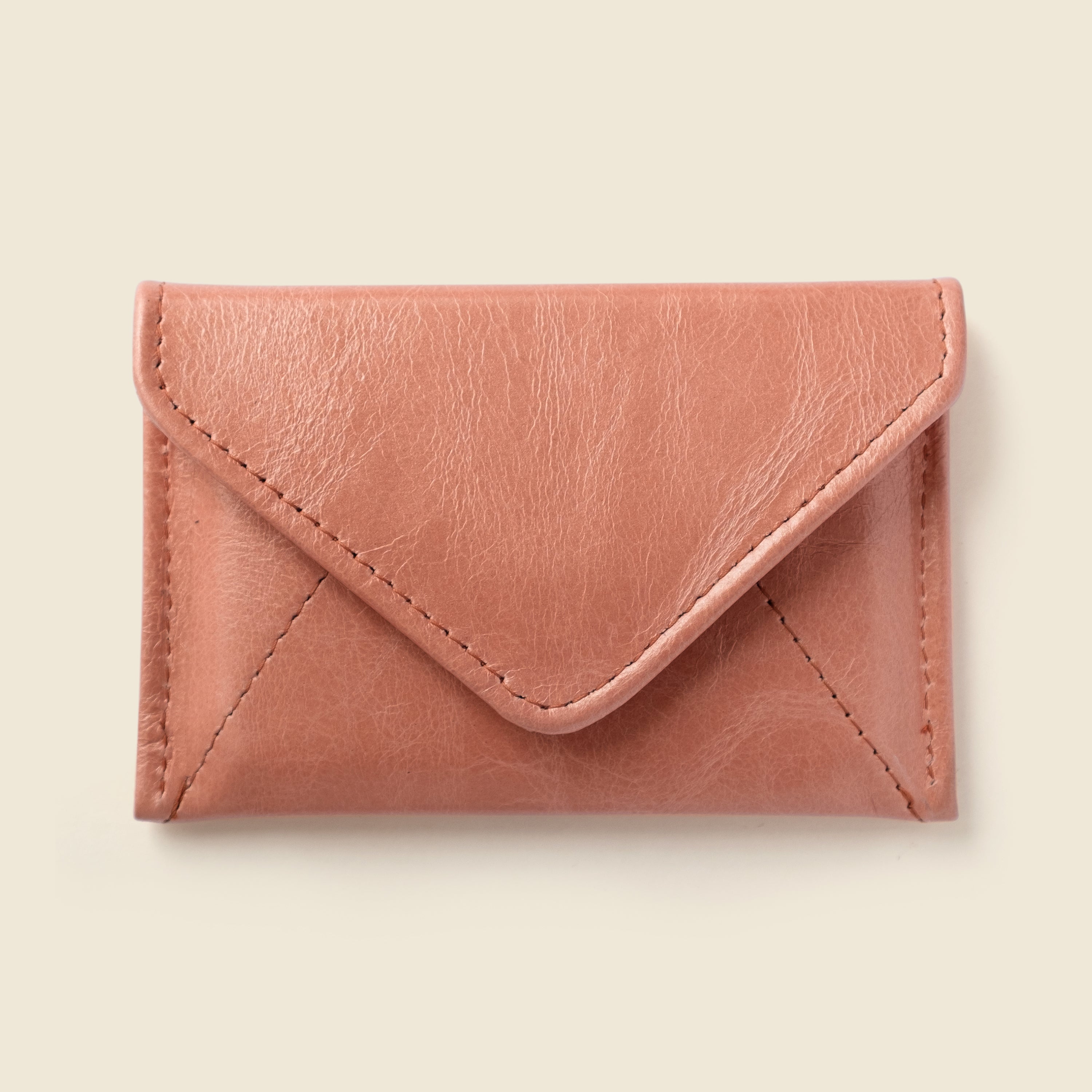 Pink leather envelope-style wallet on a beige background