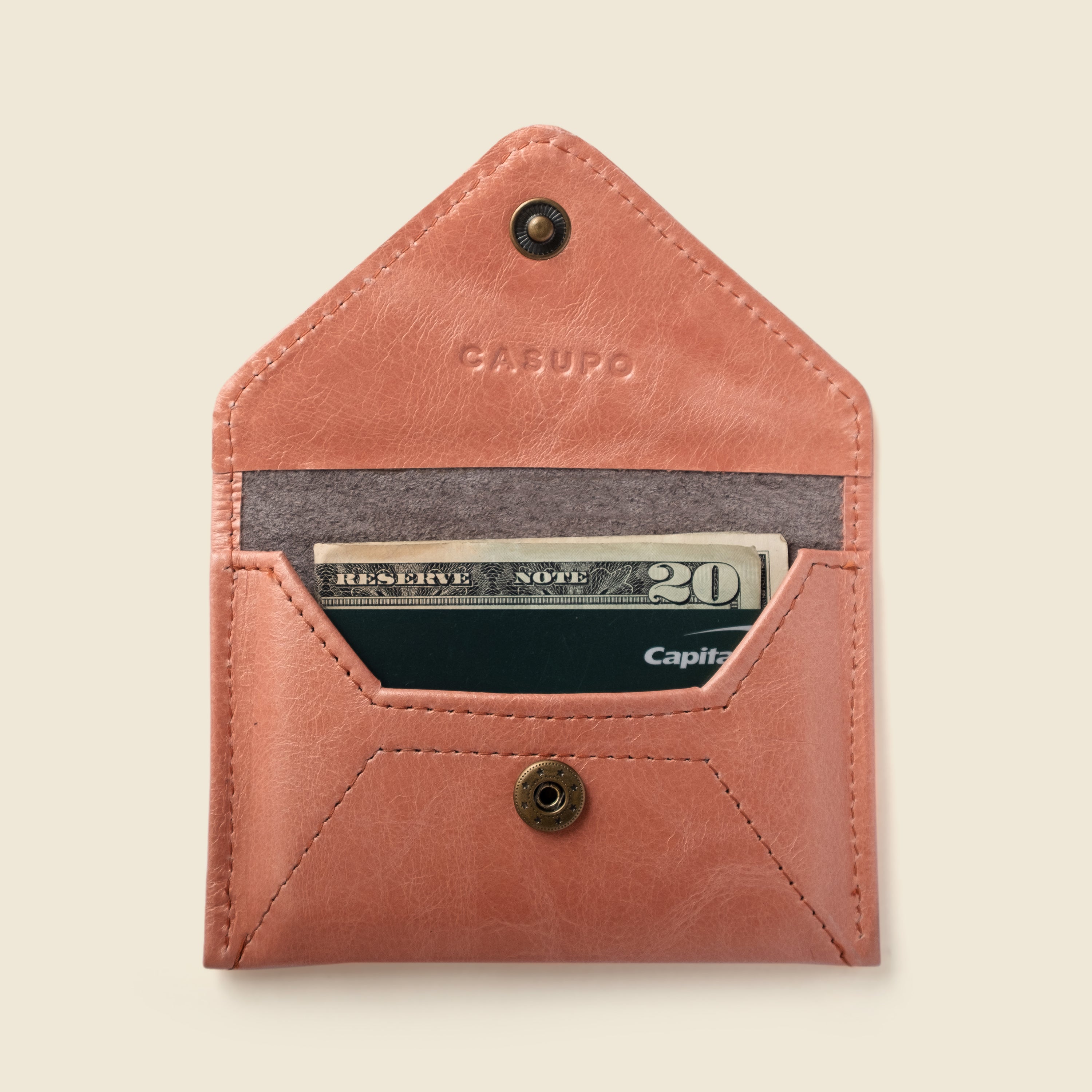 Pink leather wallet with a card and money inside on a beige background