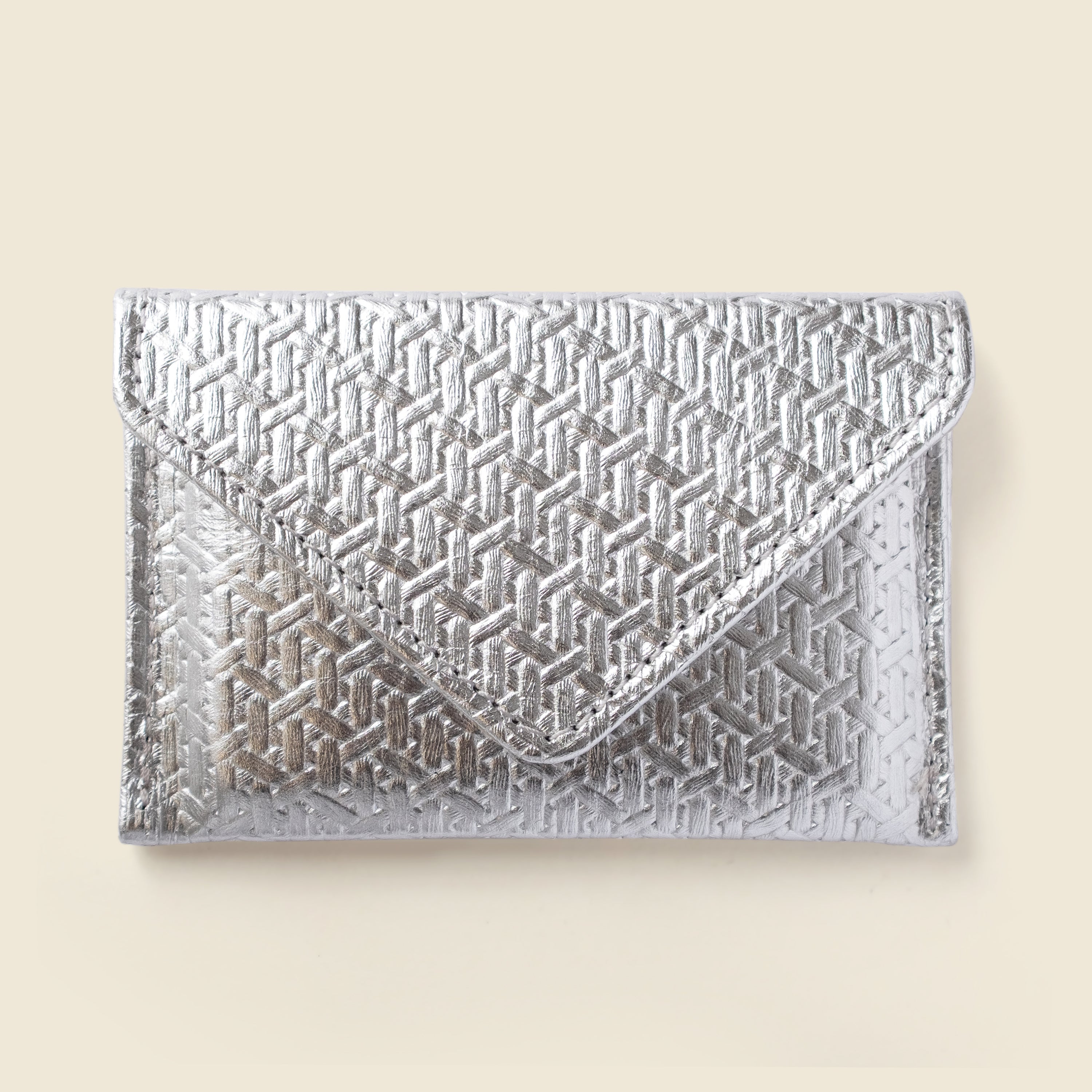 Silver geometric patterned clutch bag on a beige background