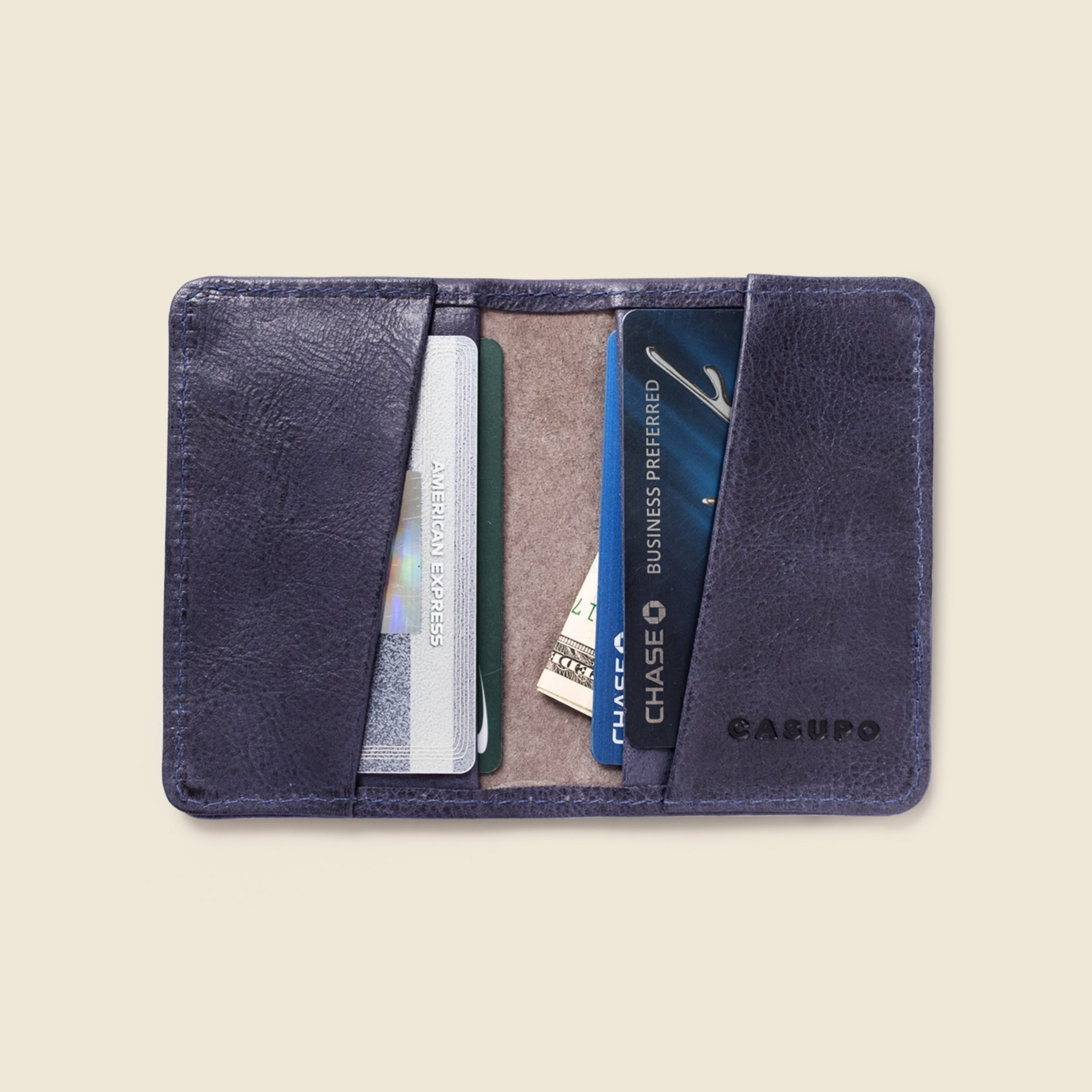 Indigo leather cardholder with cards inside on a beige background