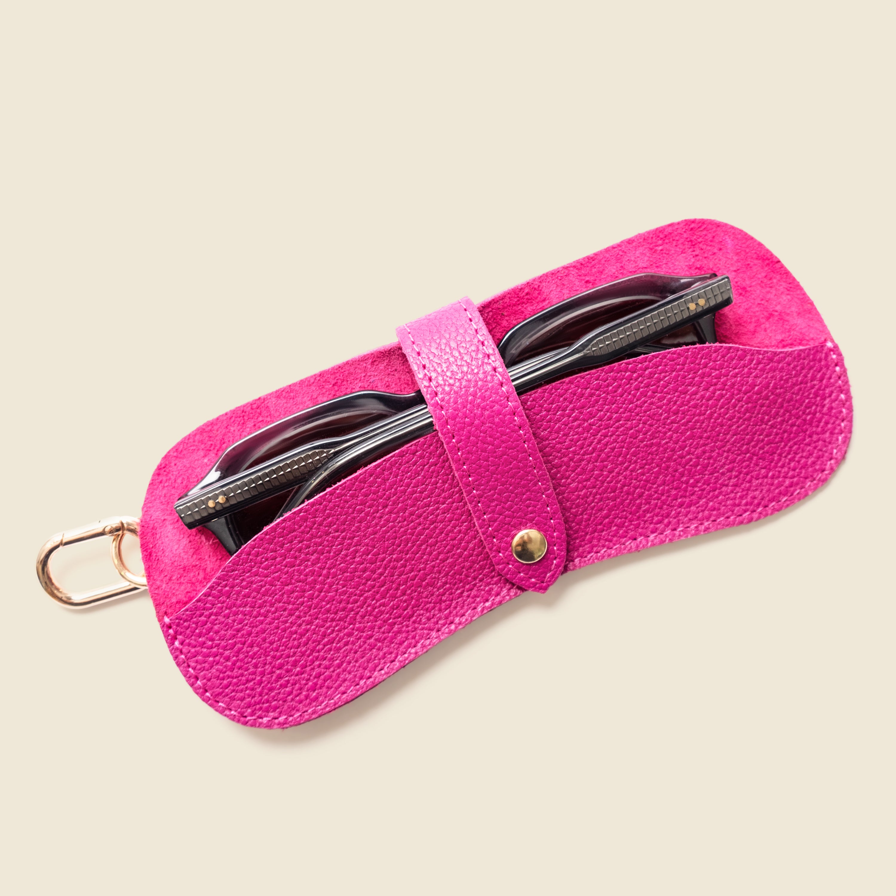 Pink sunglasses case with sunglasses inside on a beige background