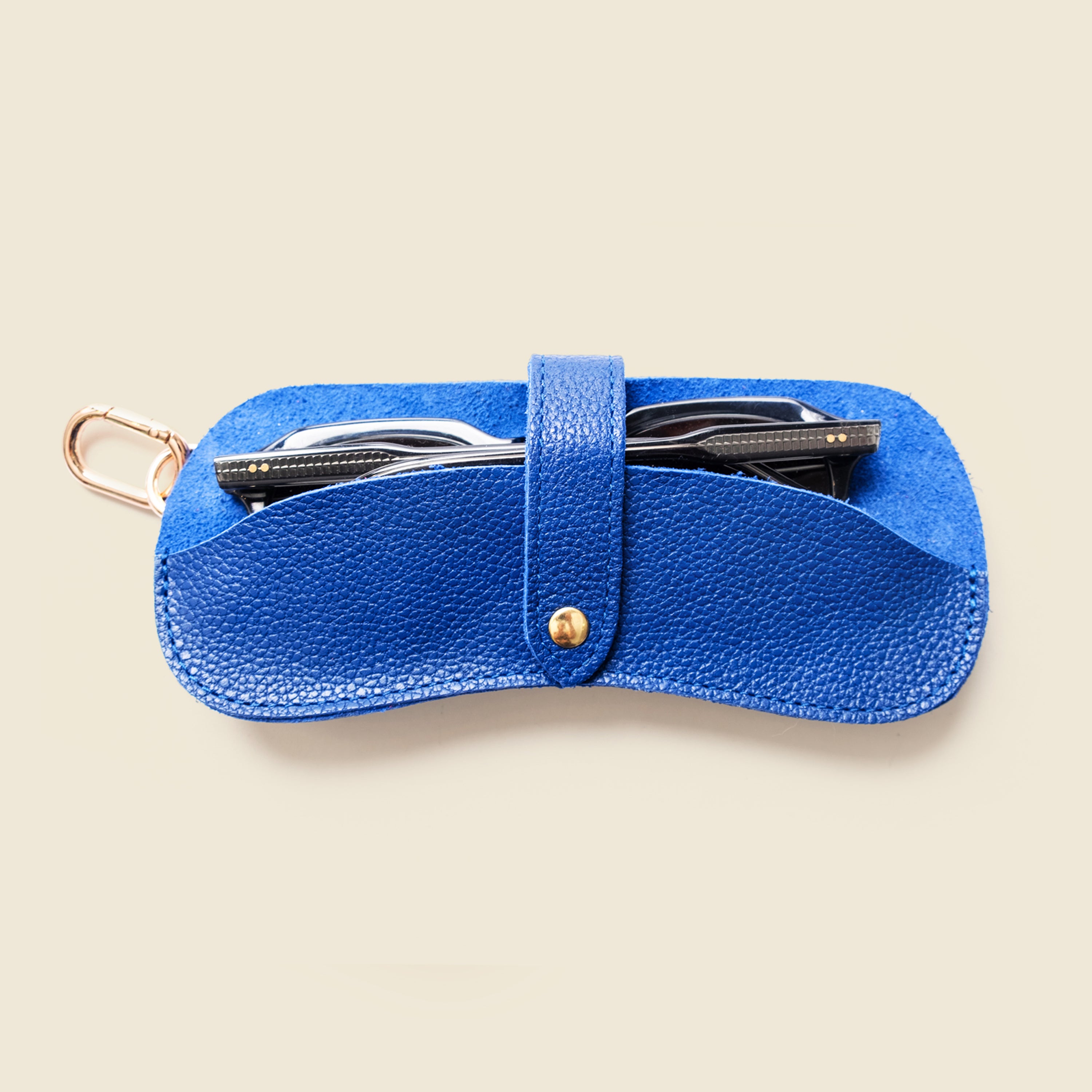 Blue leather case with sunglasses on a beige background