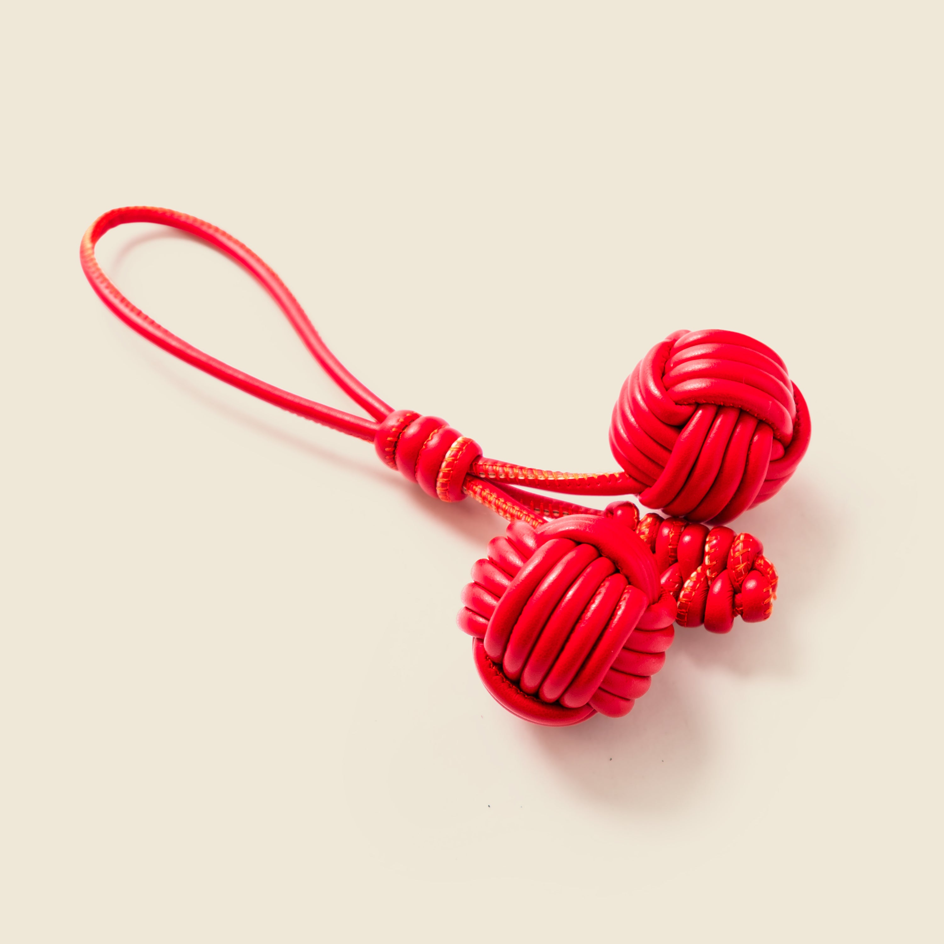 Red Leather Charm with a rope on a beige background