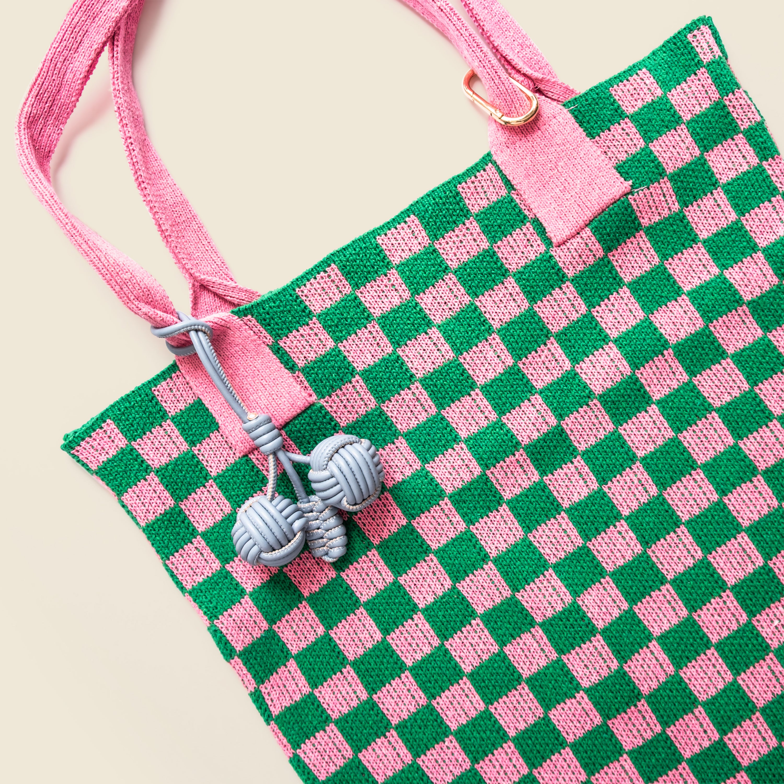 Green and pink checkered bag with a keychain on a beige background